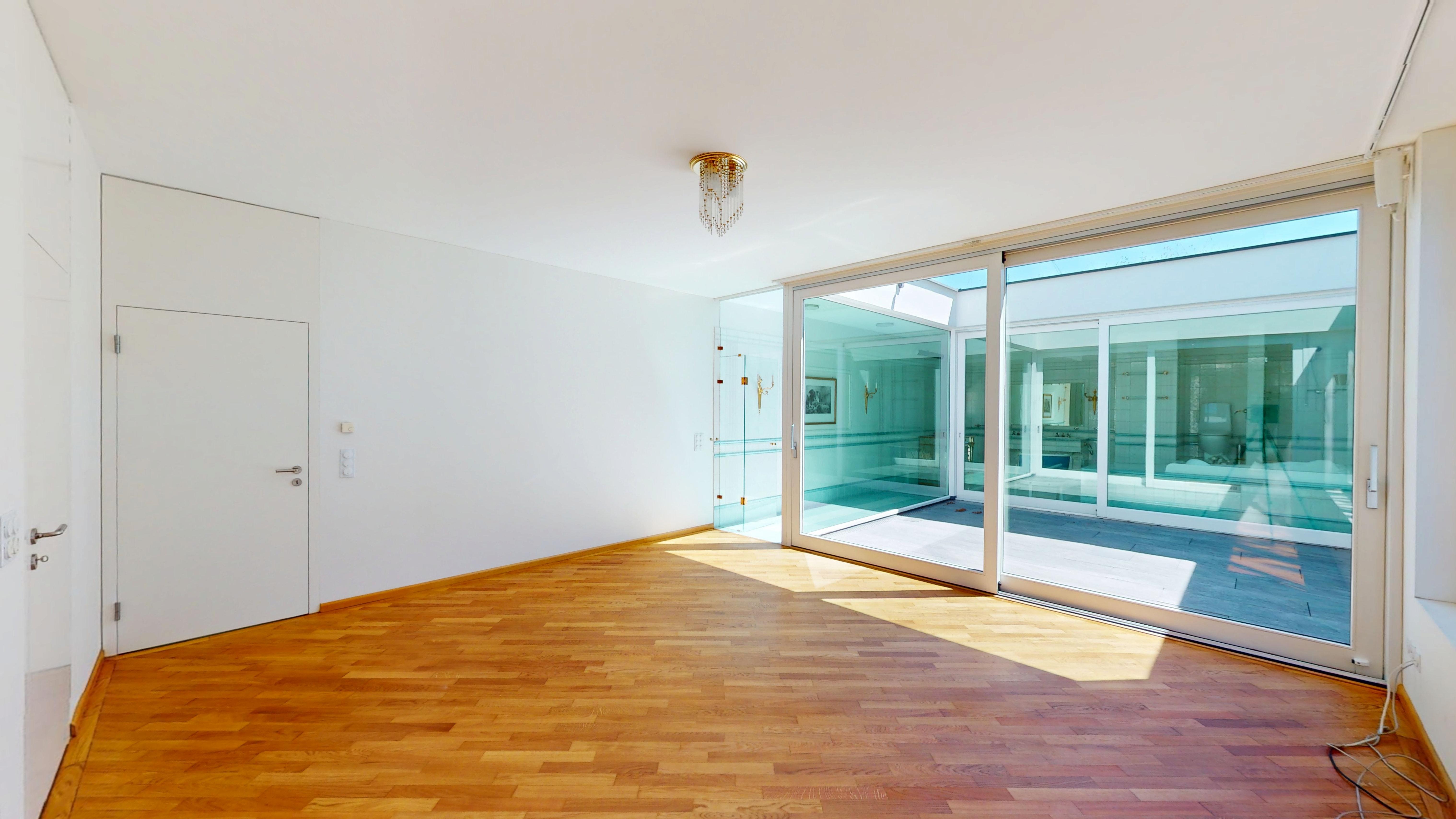 Heller leerer Raum mit Parkett und großem Glaszugang