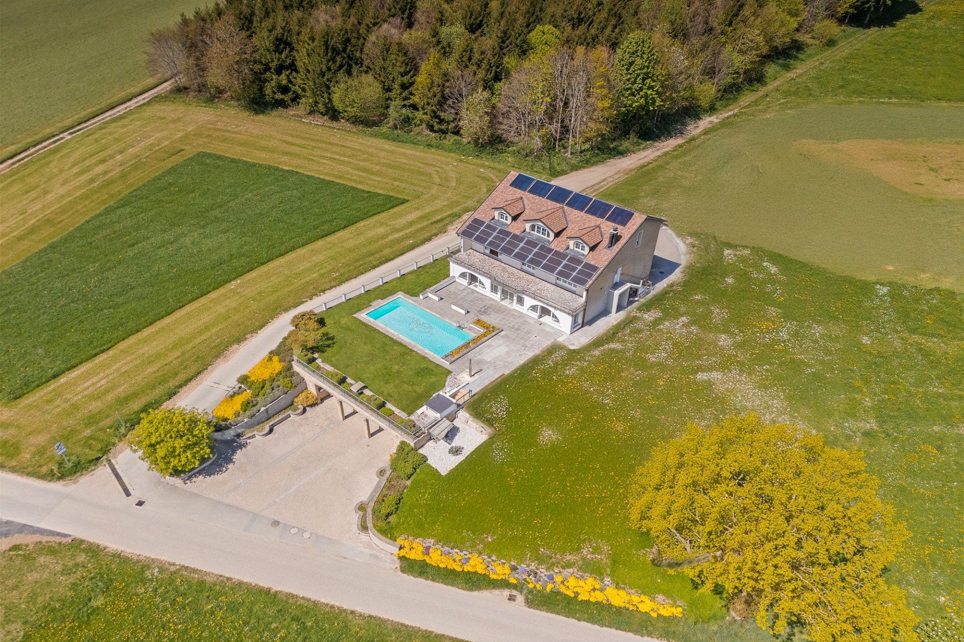 Luftaufnahme eines Landhauses mit Pool und Solaranlage
