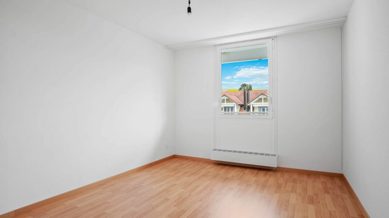 Leerer heller Raum mit Fenster und Holzoptikboden