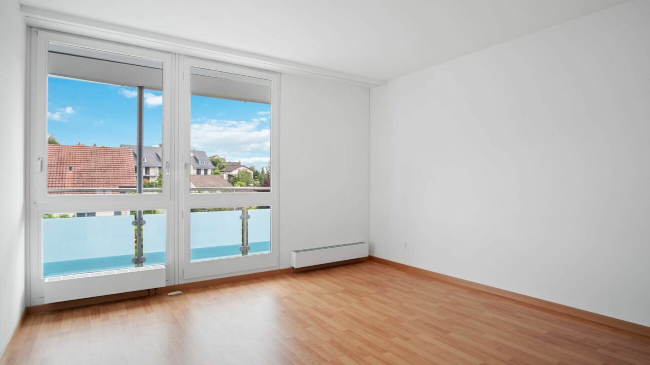Leerer, heller Wohnraum mit Balkon und großem Fenster
