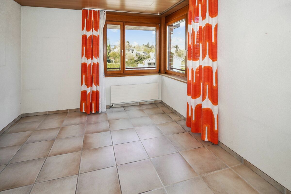 Heller Raum mit großem Fensterbereich und orangefarbenen Vorhängen