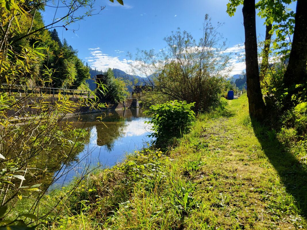 Uferweg an einem Gewässer mit Bergblick