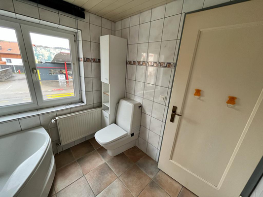 Badezimmer mit Wanne, WC und Fenster