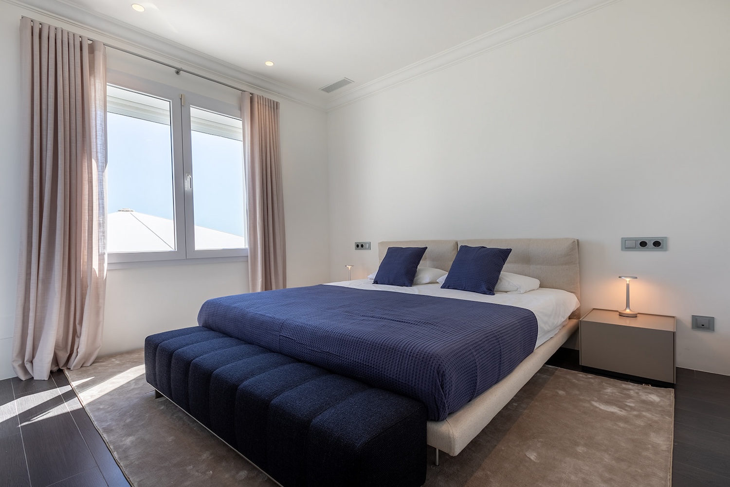 Modernes Schlafzimmer mit Doppelbett und großen Fenstern