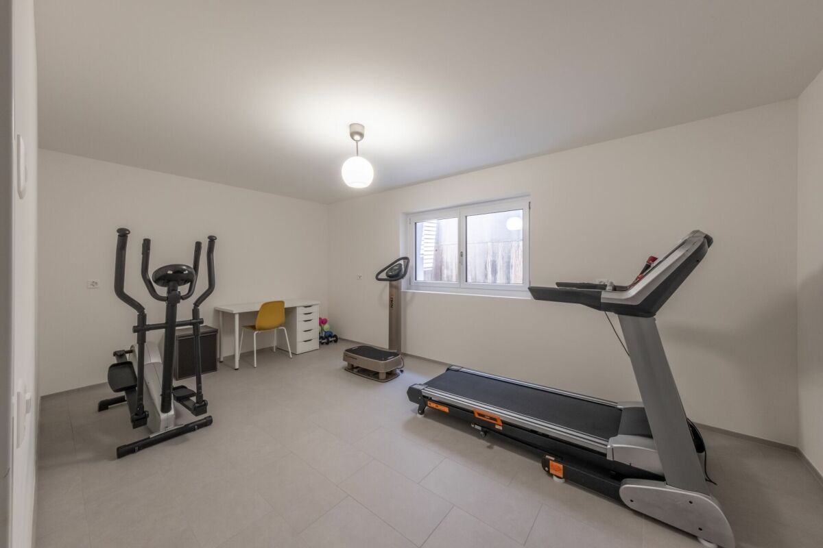 Heller Fitnessraum mit Laufband und Crosstrainer