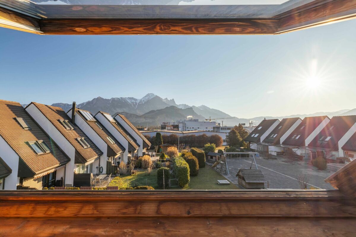 Balkon- oder Dachfensterblick auf Wohnsiedlung mit Bergpanorama