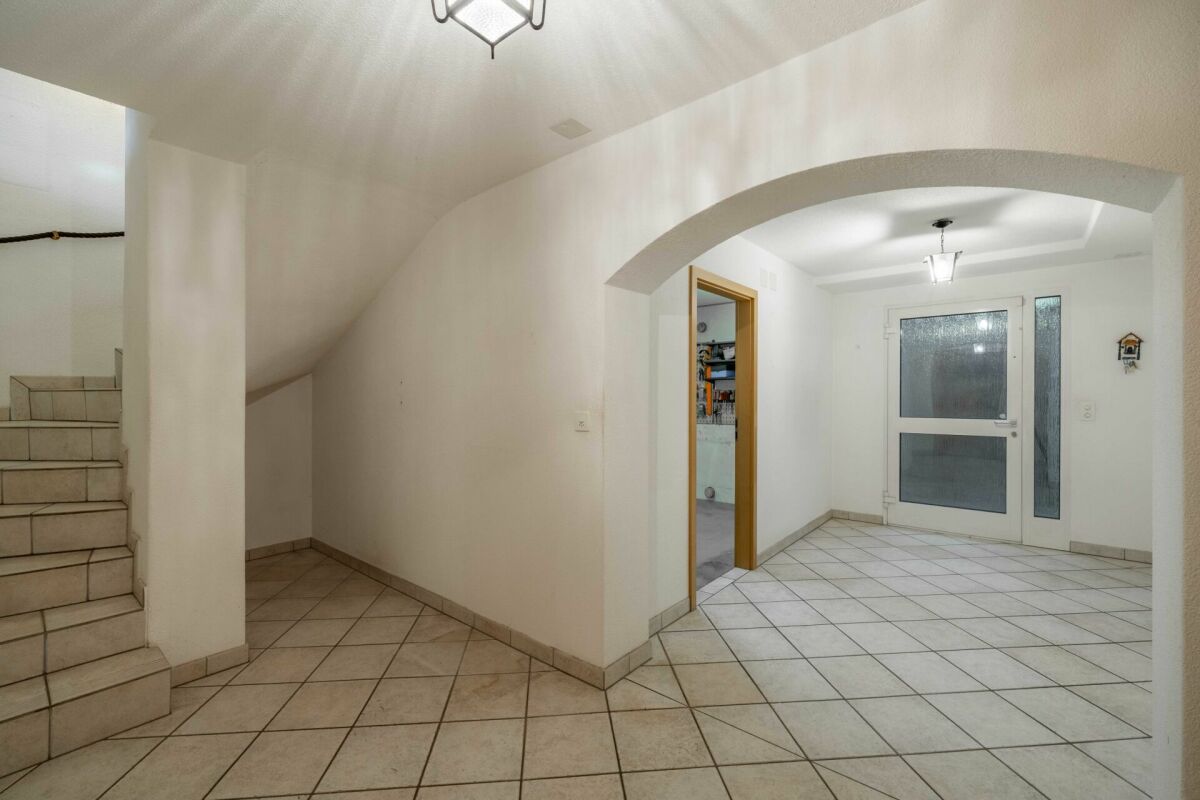 Heller Eingangsbereich mit Treppe und Rundbogen