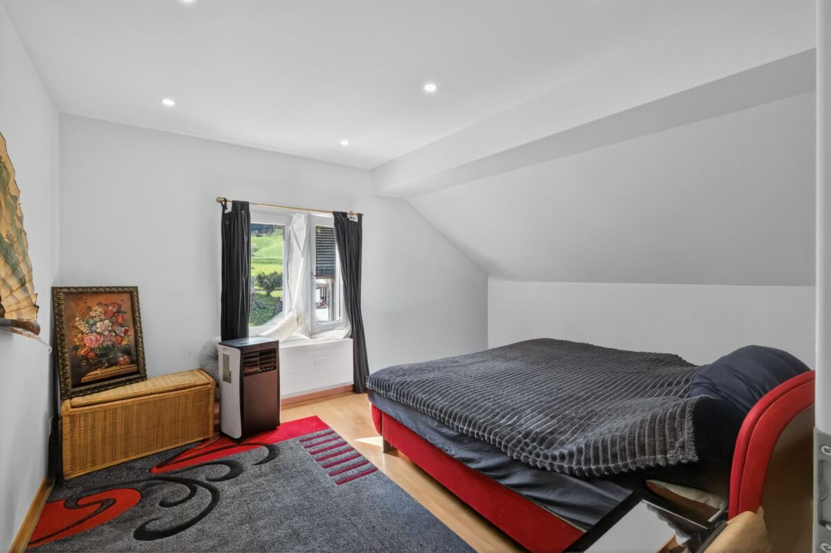 Schlafzimmer im Dachgeschoss mit Bett, Fenster und Teppich