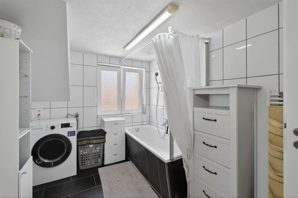 Badezimmer mit Waschmaschine und Badewanne