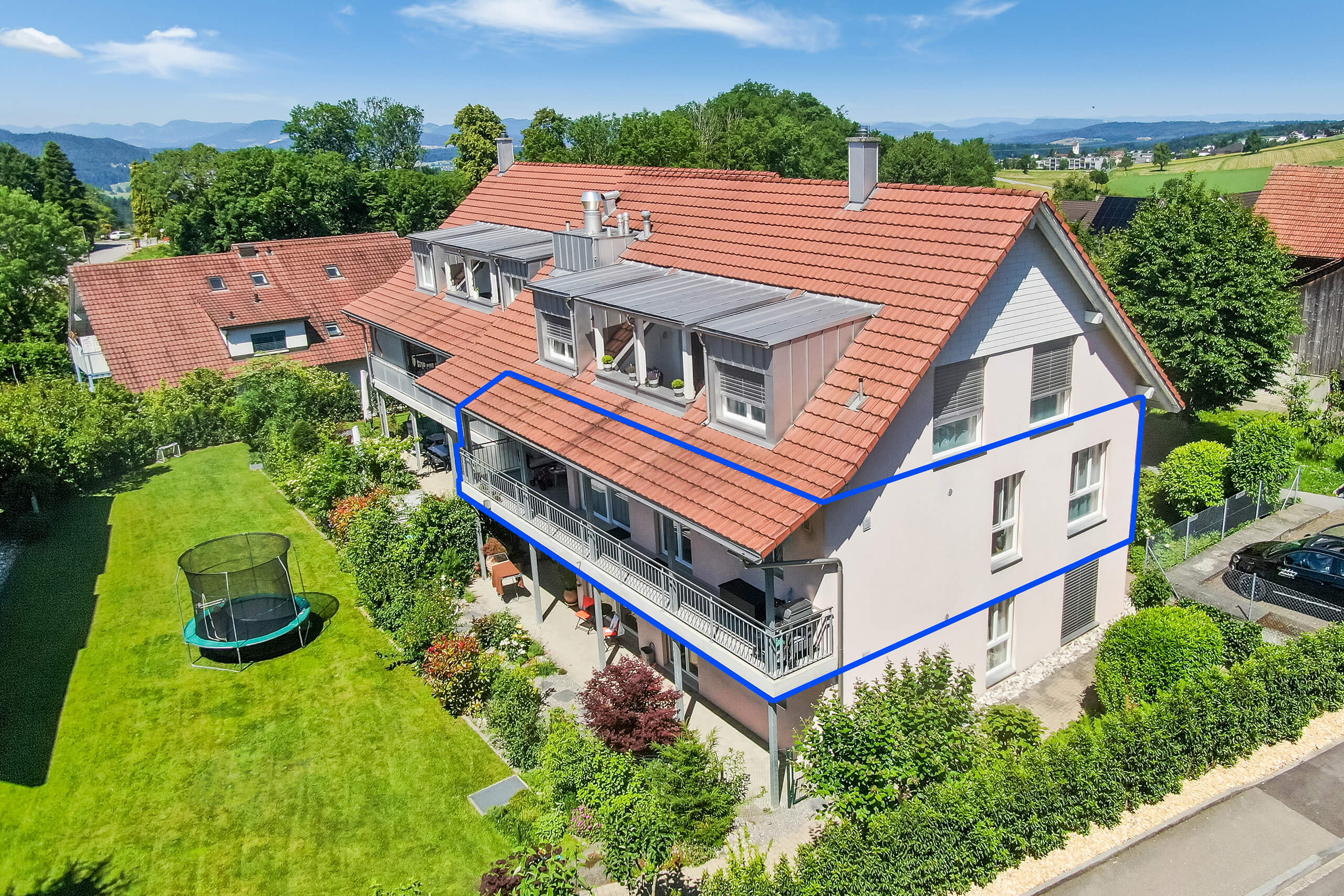Luftaufnahme eines Mehrfamilienhauses mit Garten und Balkon