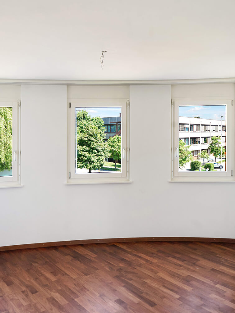 Leerer Raum mit drei Fenstern und Holzboden