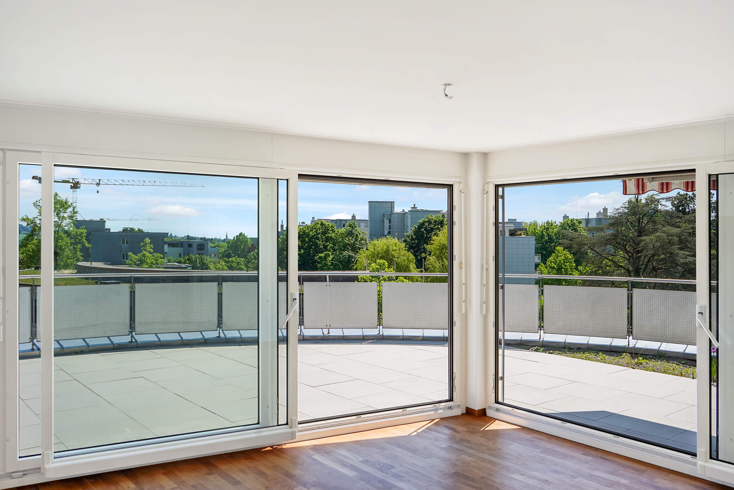 Heller Wohnraum mit großer Fensterfront und Balkonblick