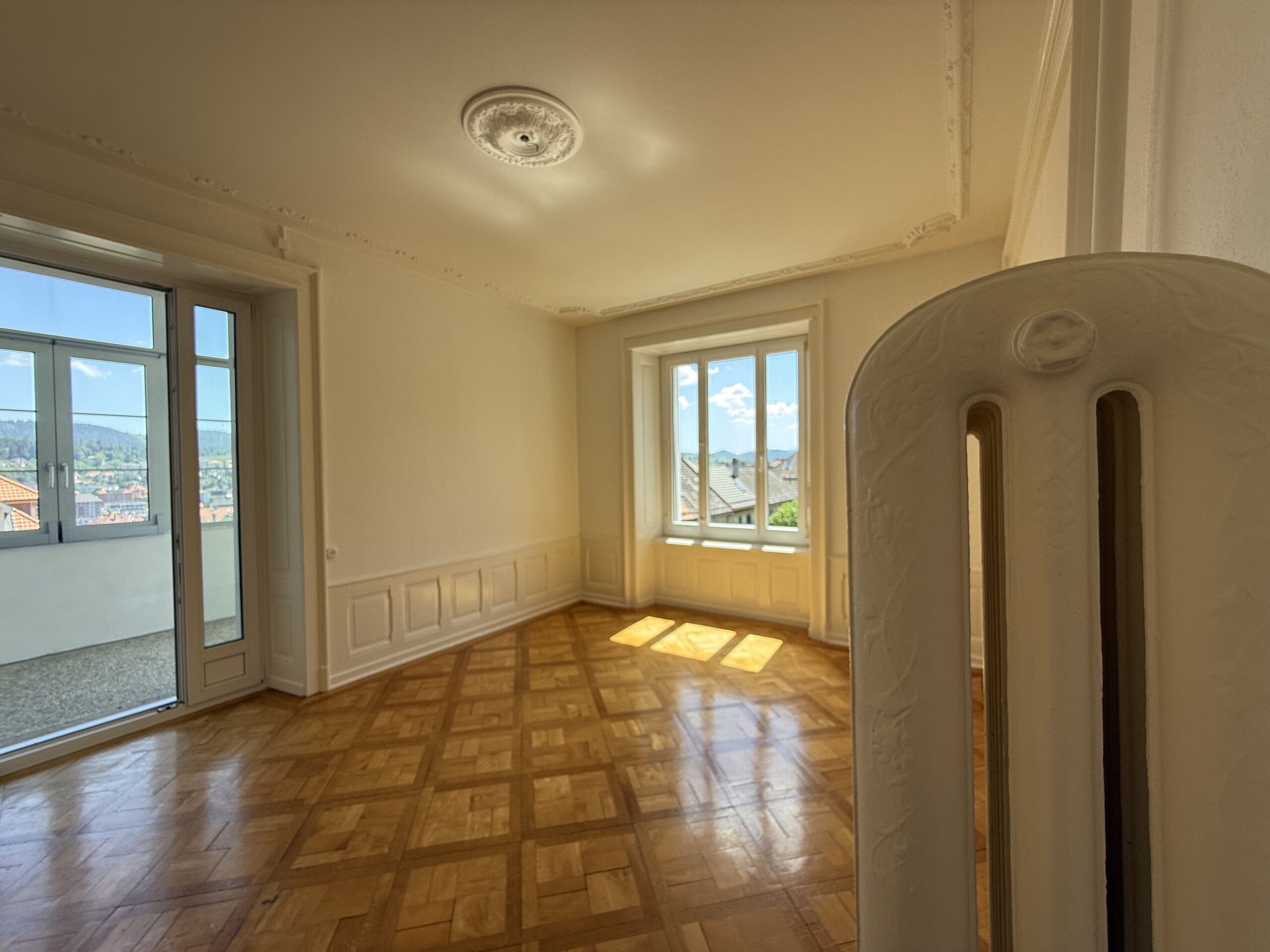 Heller, leerer Altbau-Raum mit Stuck und Parkett