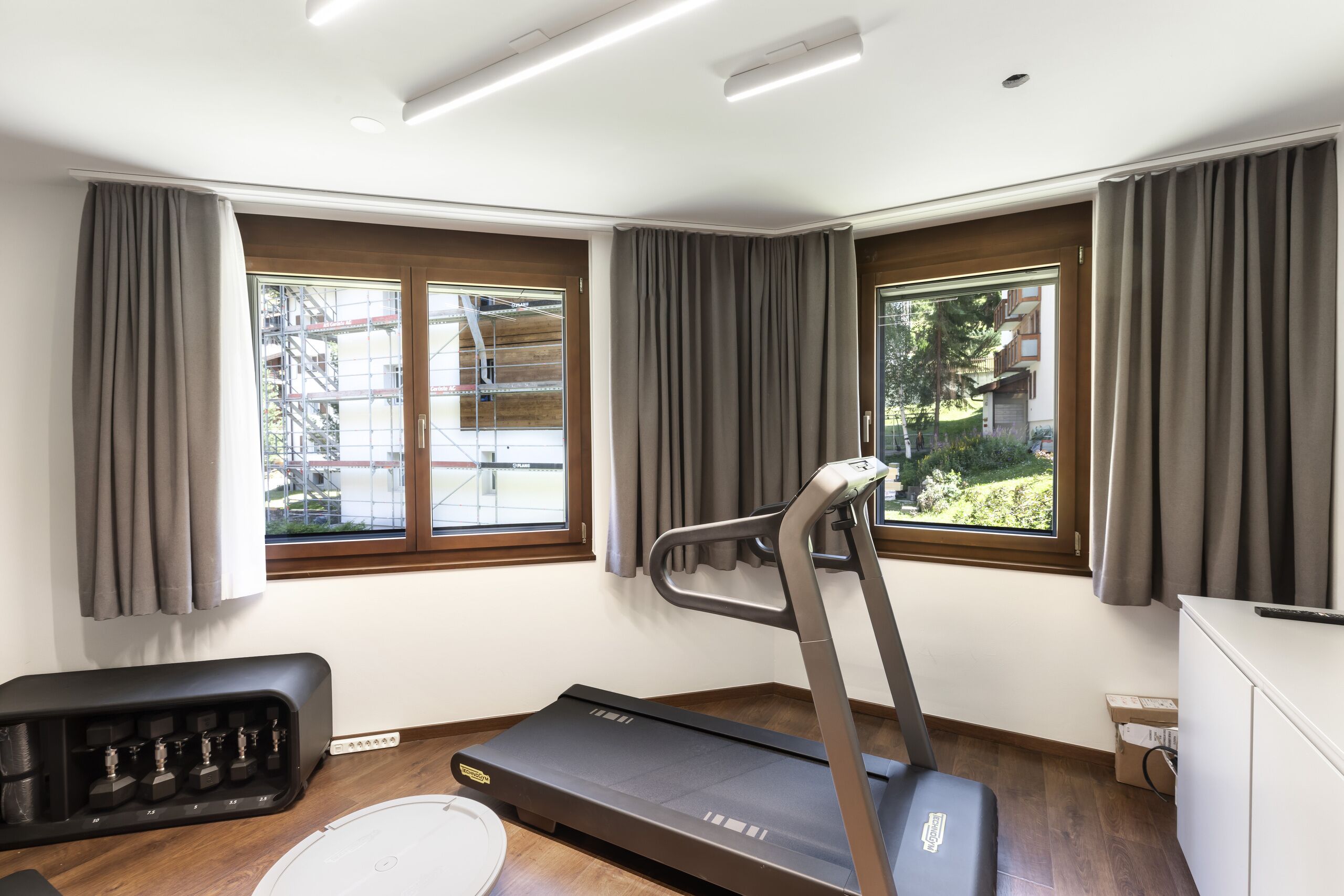 Fitnessraum mit zwei Fenstern und Trainingsgeräten