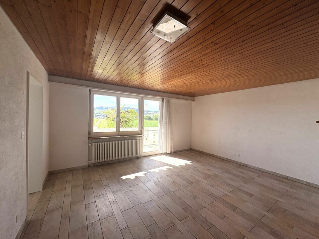 Heller leerer Raum mit Holzdecke und Balkonblick