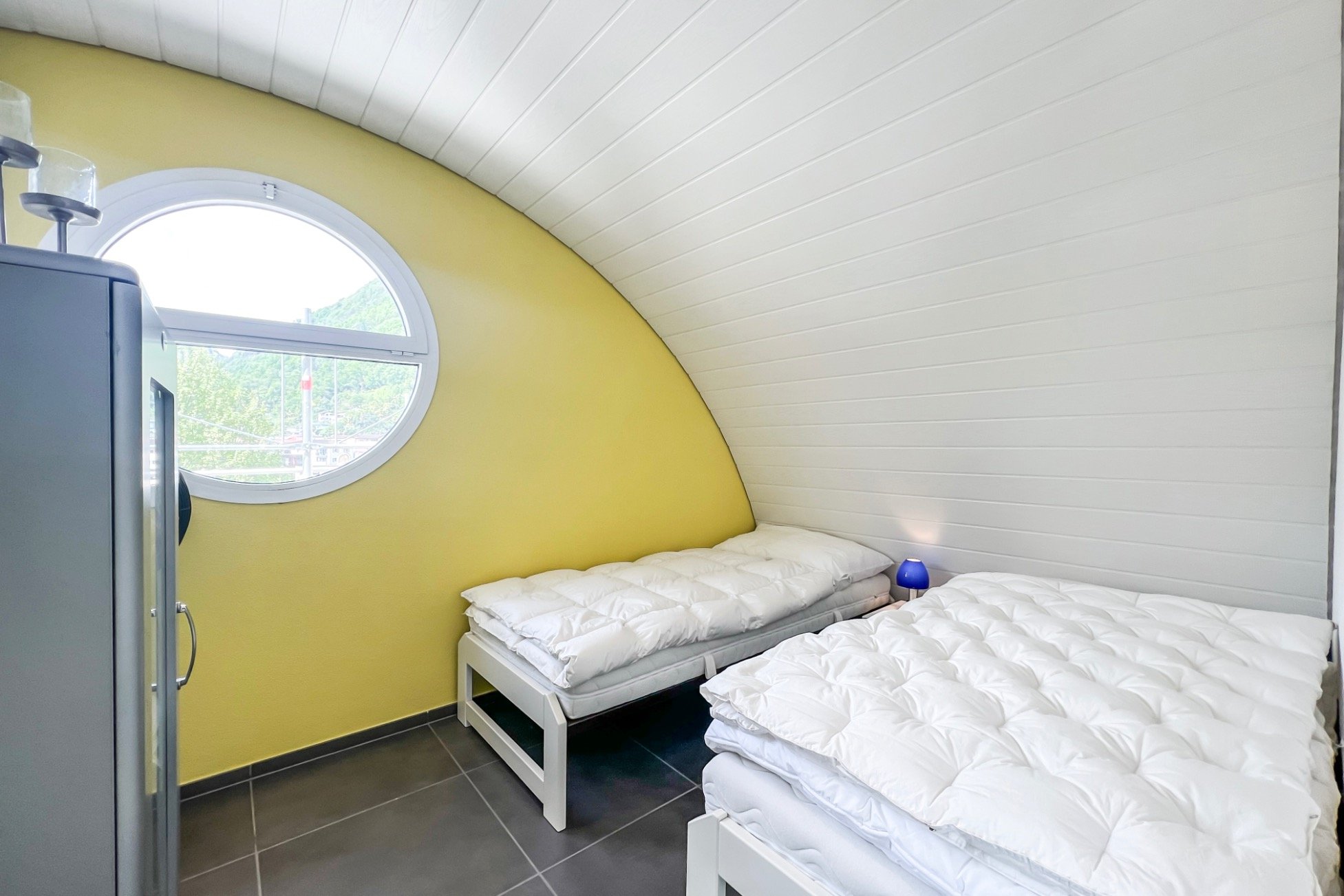 Kleines Schlafzimmer mit runder Fensteröffnung