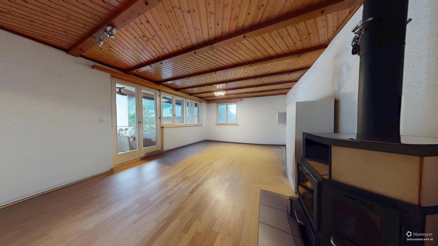 Großer leerer Wohnraum mit Holzdecke und Kamin