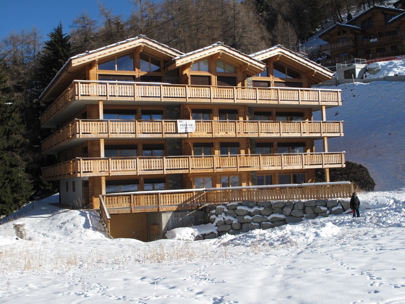 Alpenchalet mit großen Holzbalkonen im Schnee
