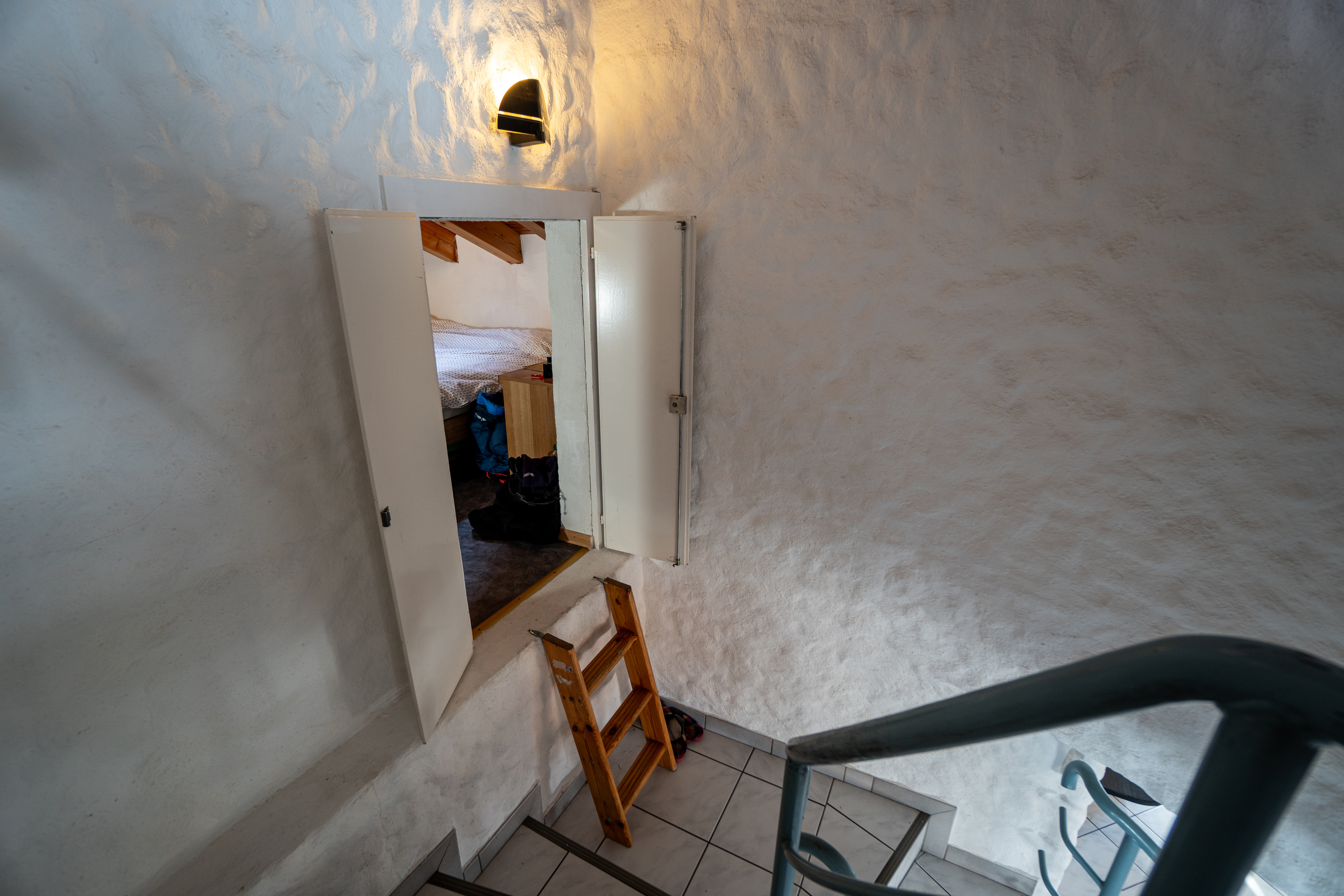 Treppenhaus mit Holztür und Rauputzwänden