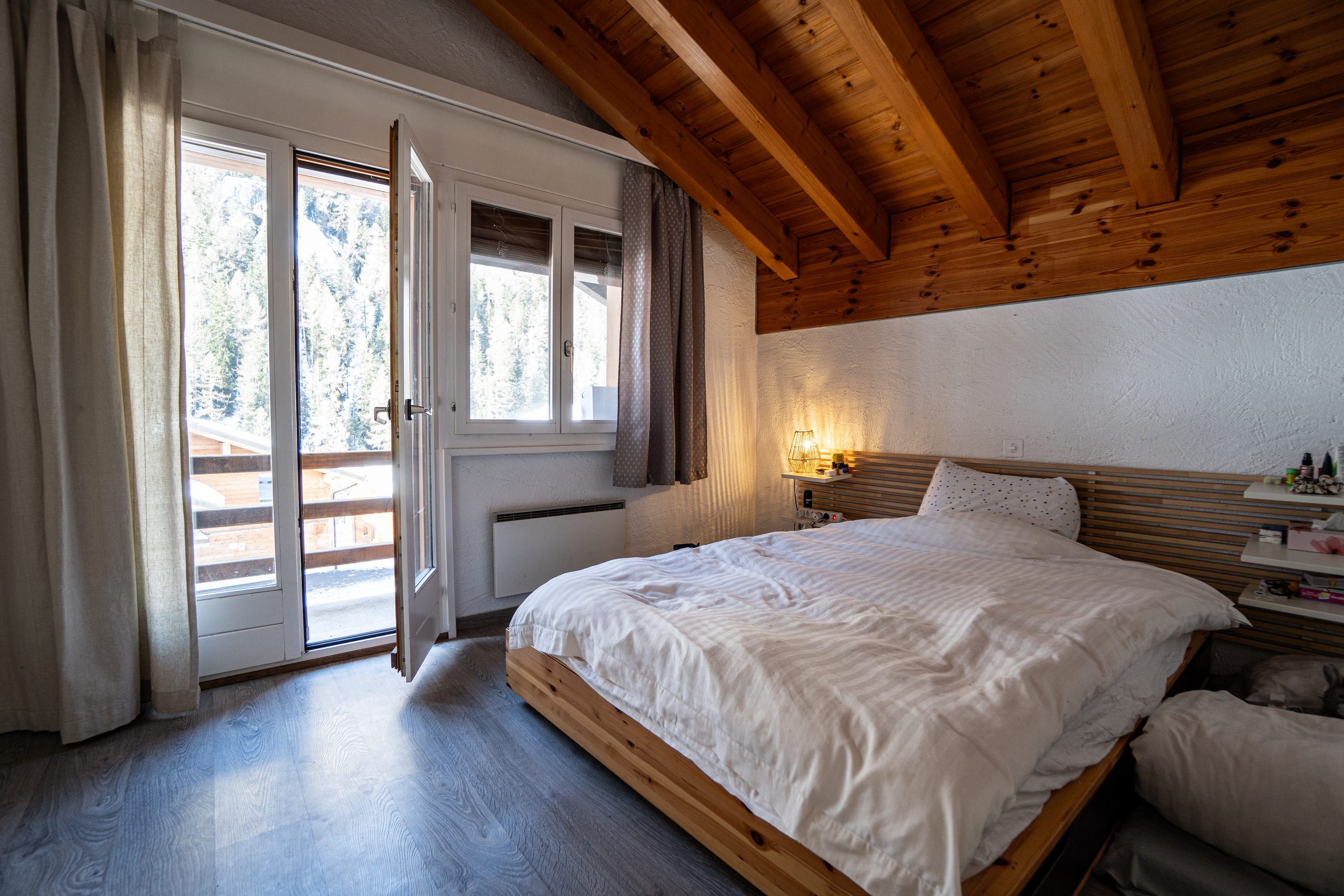 Gemütliches Schlafzimmer mit Holzdecke und Balkonzugang
