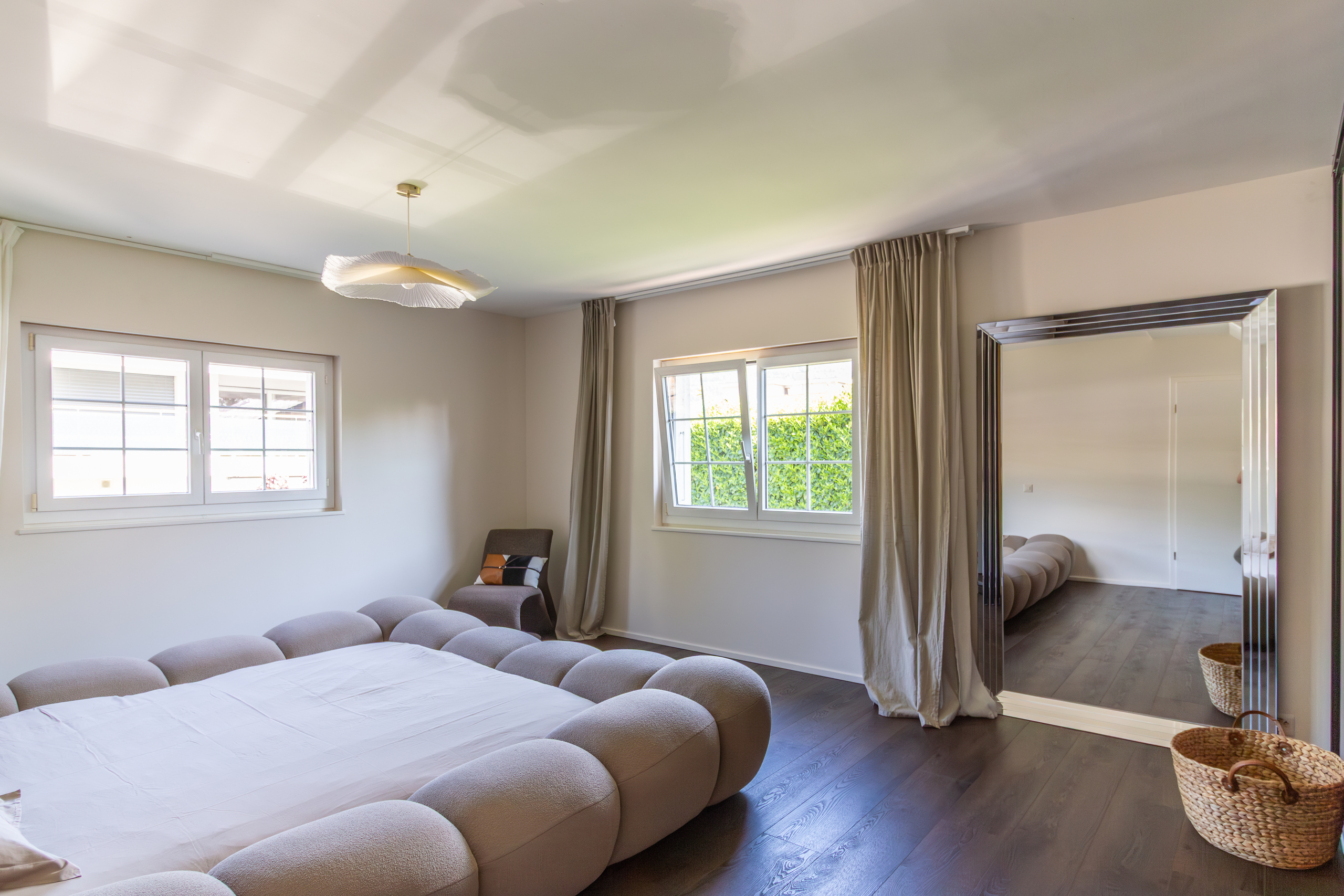 Helles Schlafzimmer mit großem Spiegel und dunklem Holzboden
