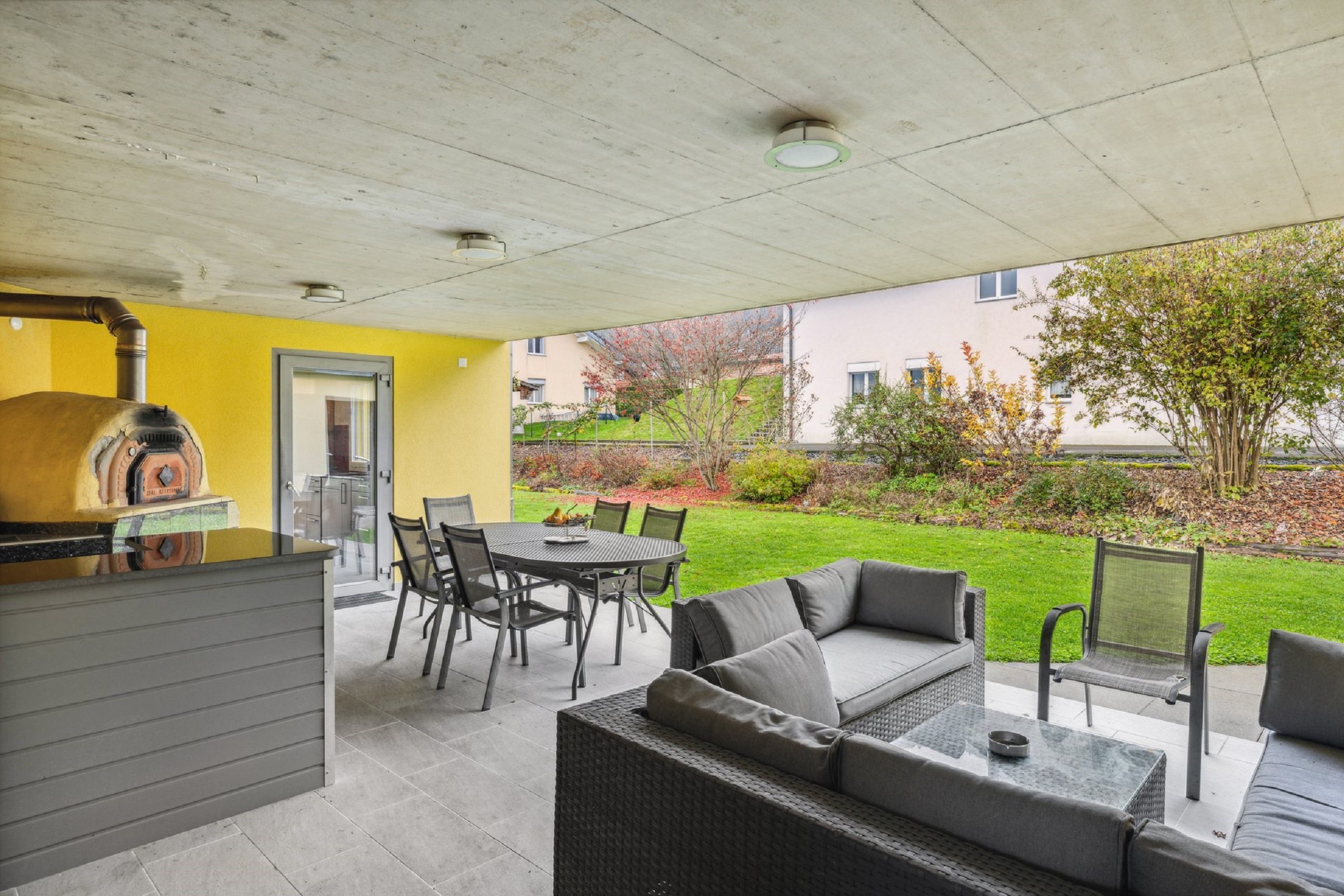 Überdachte Terrasse mit Grill und Gartenmöbeln