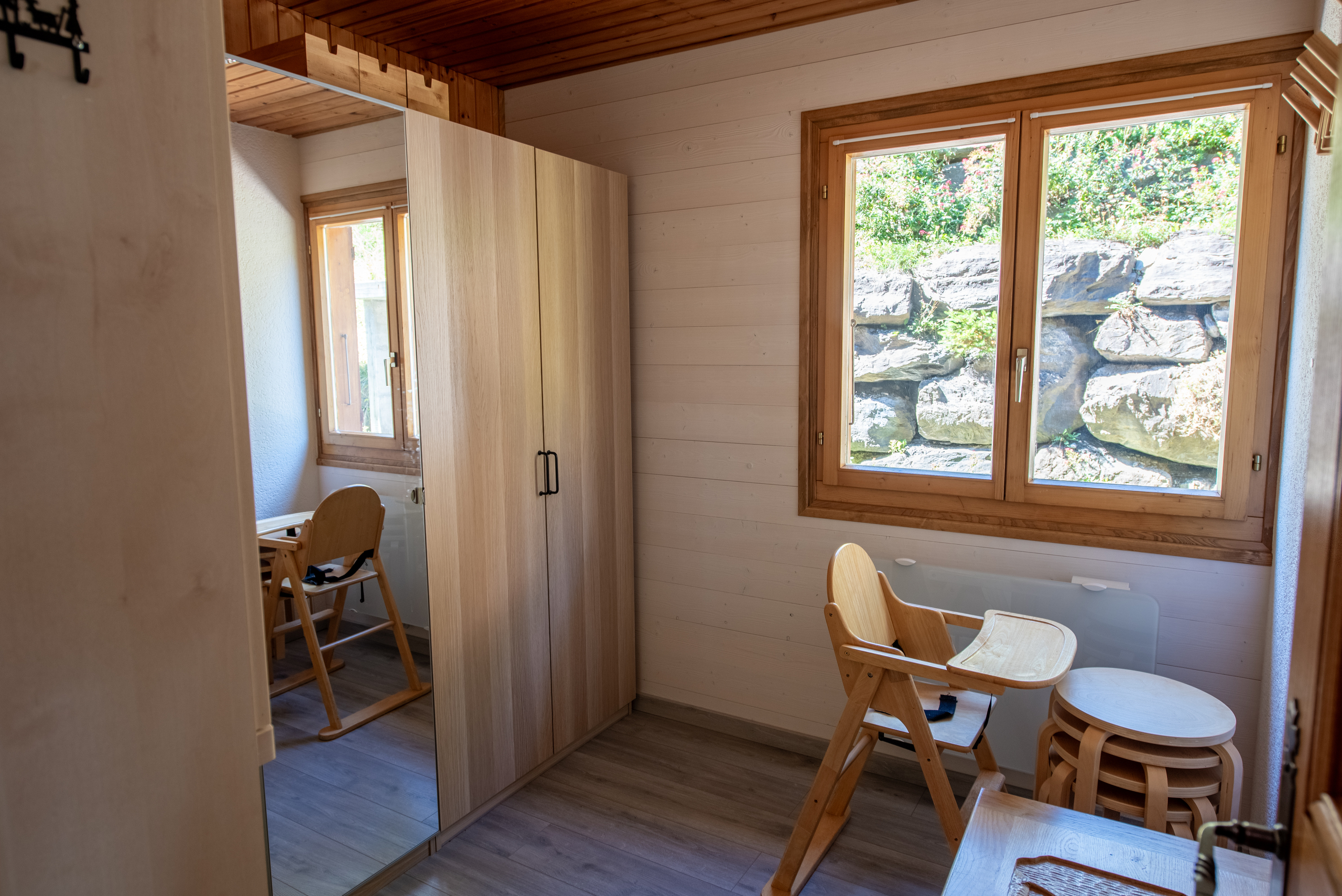 Helles Holz-Zimmer mit großem Fenster und Kleinkindmöbeln