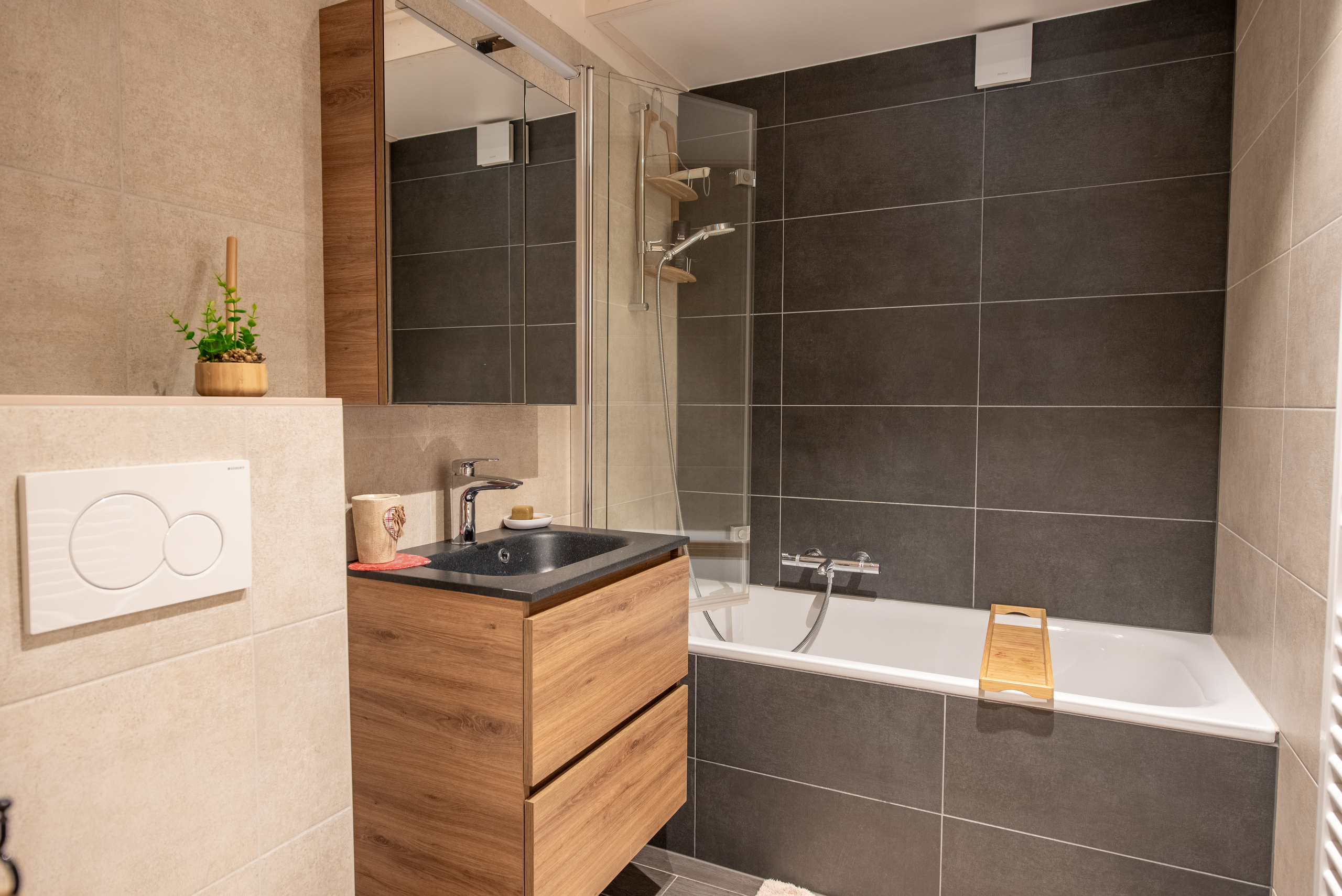 Modernes Badezimmer mit Badewanne und dunkler Fliesenwand