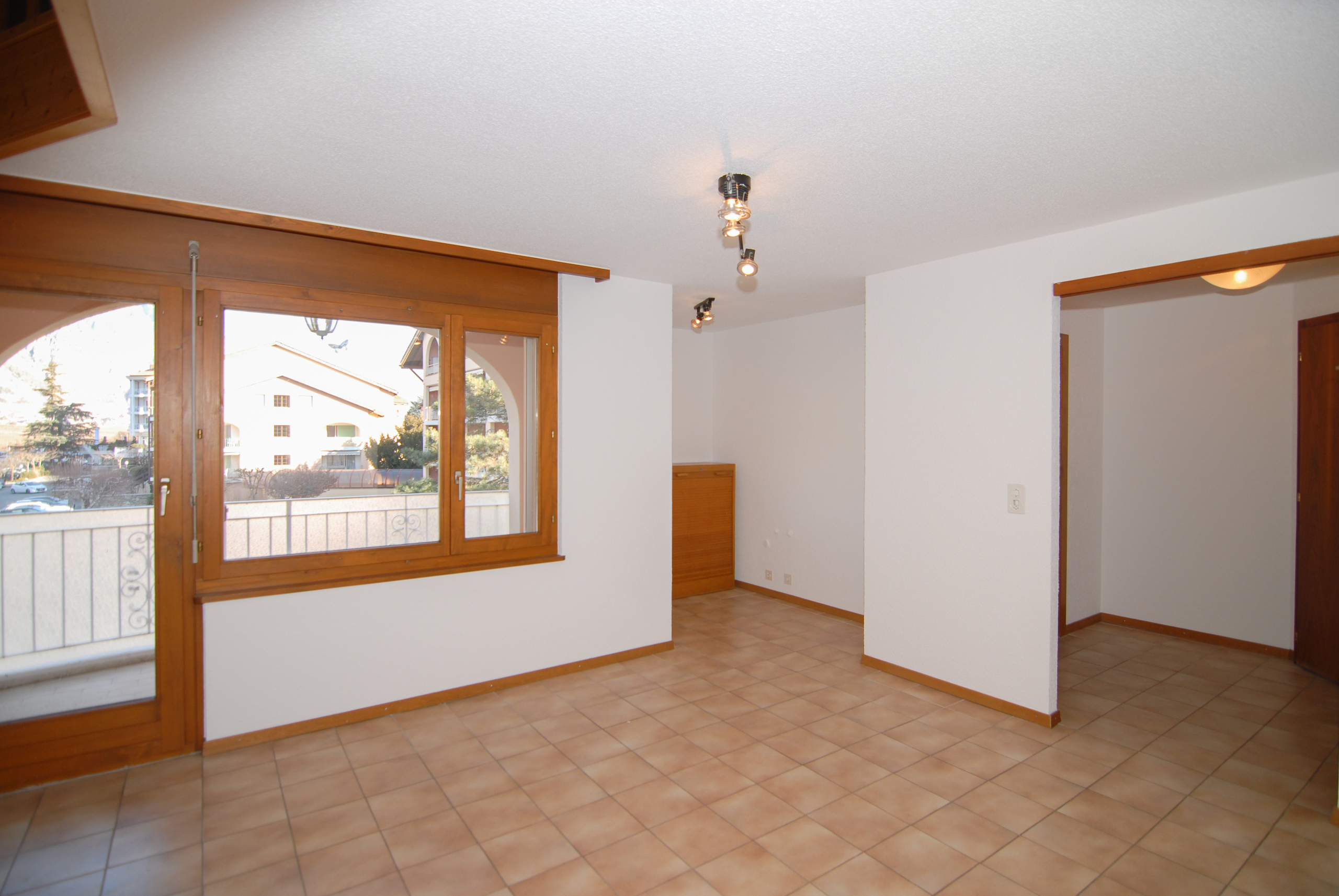Heller leerer Wohnraum mit Terrasse und großen Holzfenstern