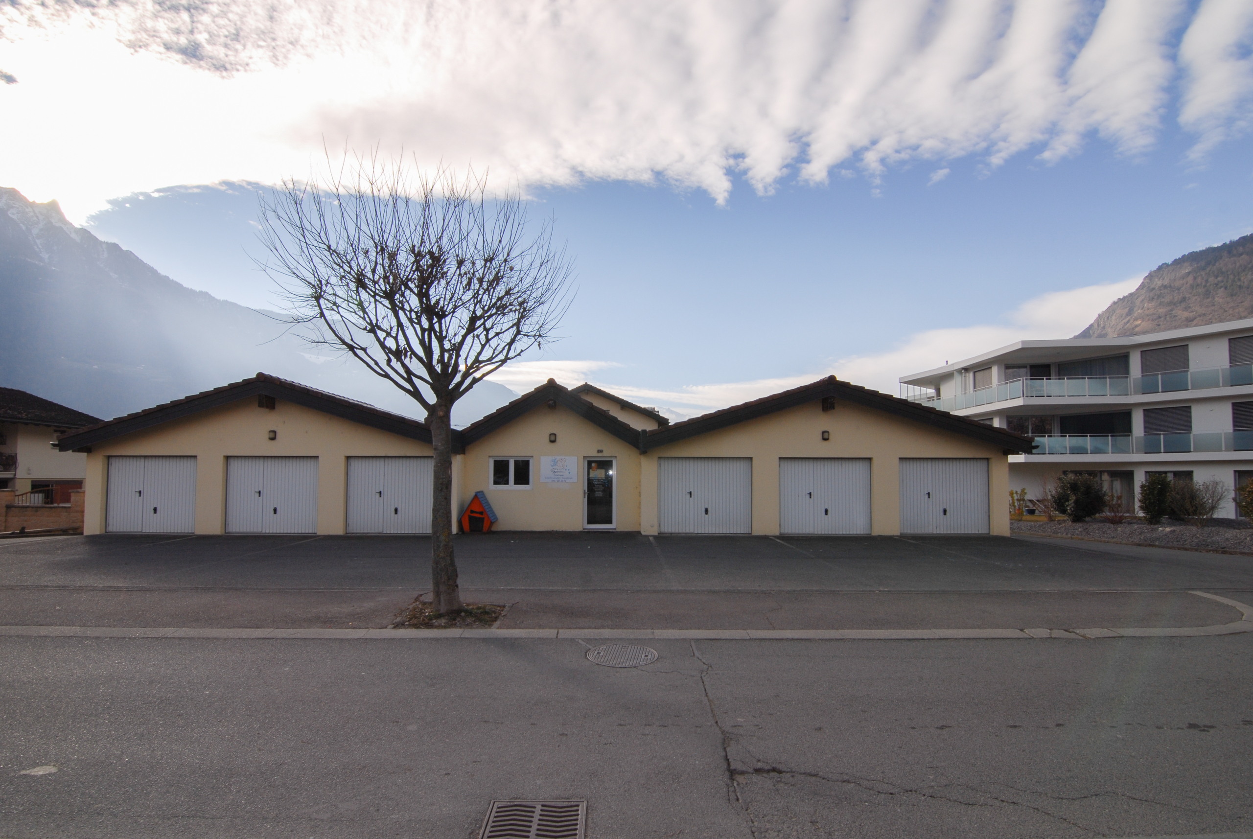 Wohngebäude mit Garagenzeile vor Bergkulisse