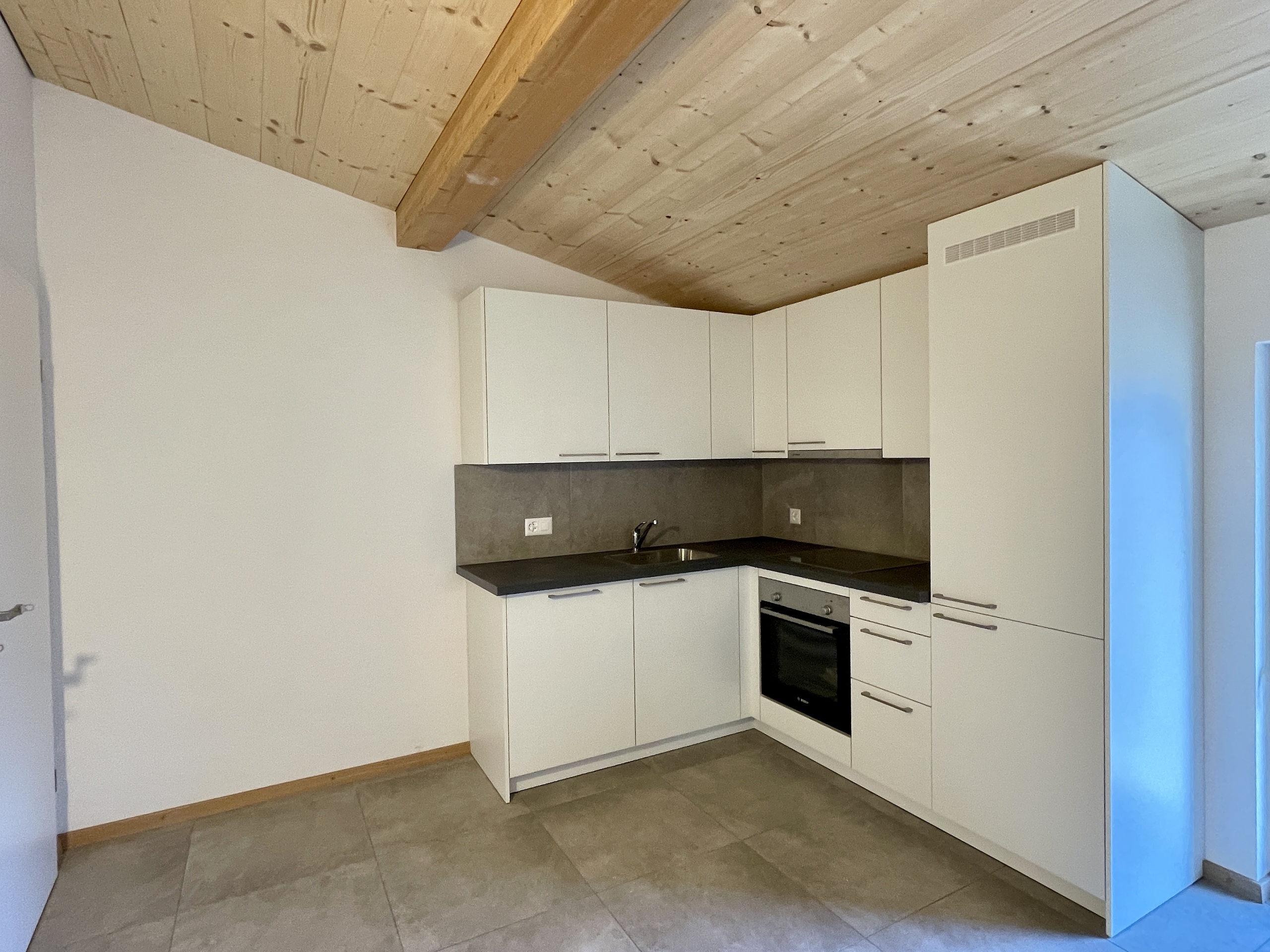 Moderne Küchenzeile unter Holzbalkendecke