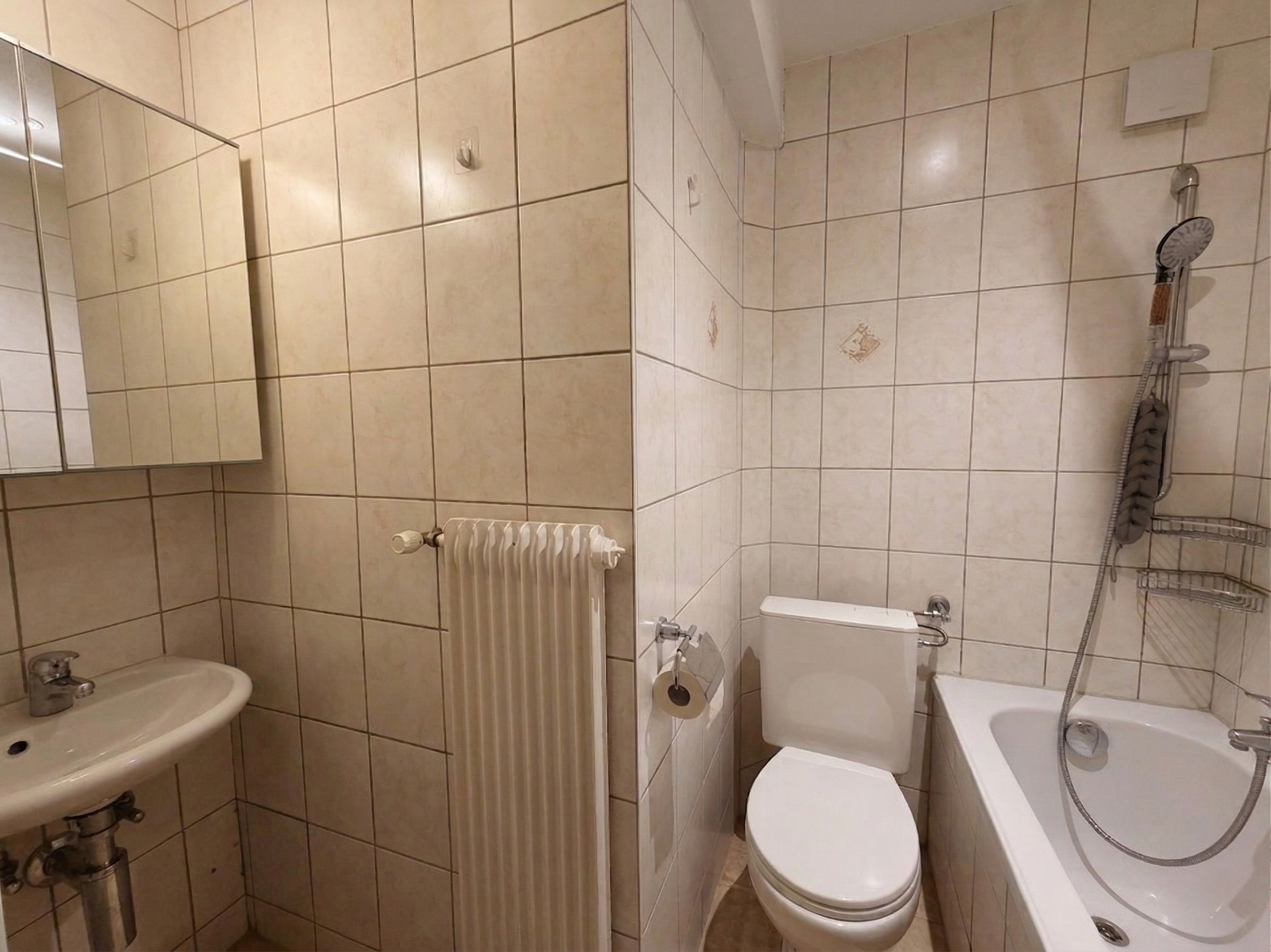 Kleines Badezimmer mit Badewanne, WC und Wandwaschbecken