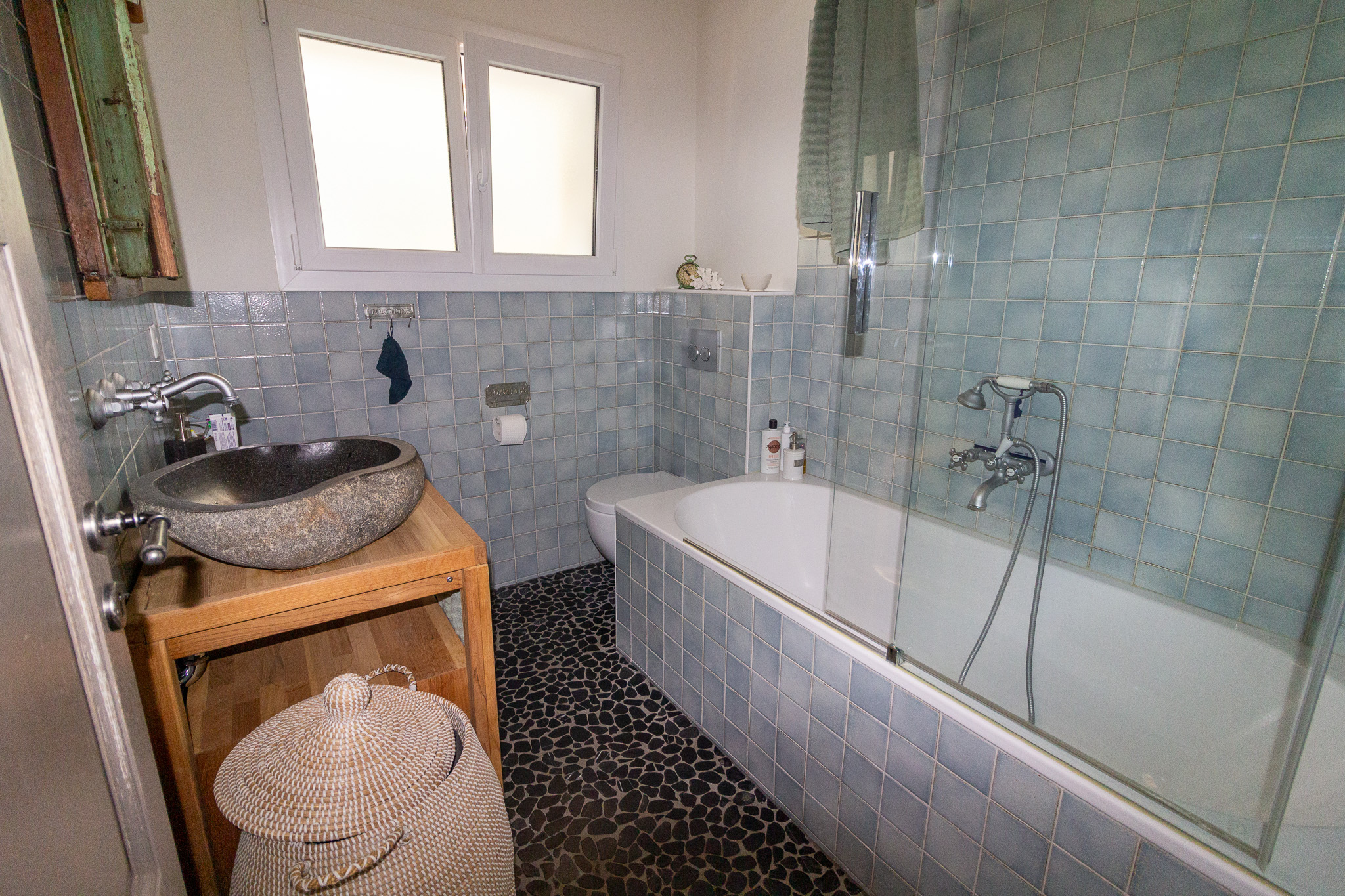 Badezimmer mit Badewanne und Natursteinwaschbecken