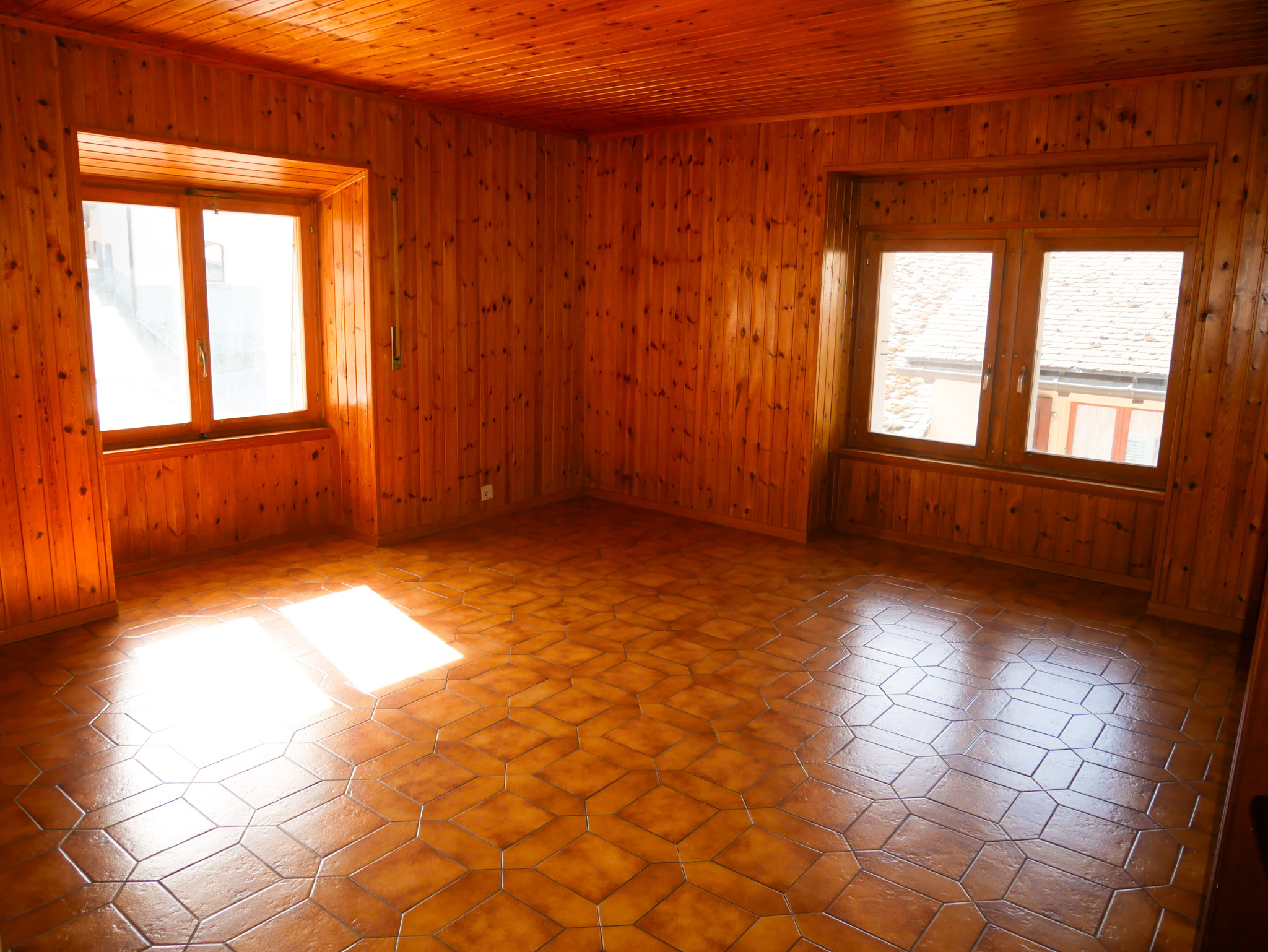 Leerer, holzverkleideter Raum mit großen Fenstern