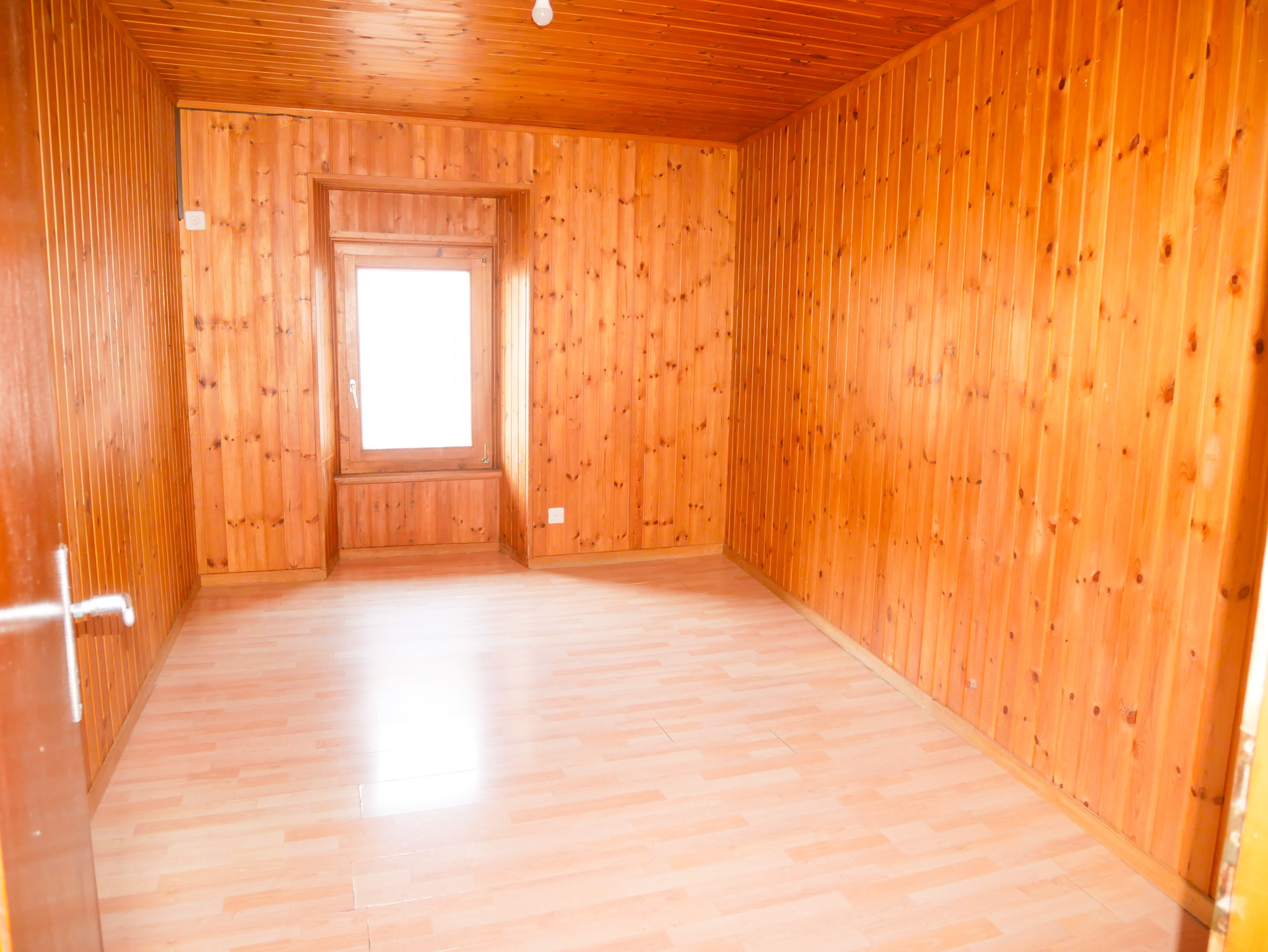 Leerer holzverkleideter Raum mit Fenster