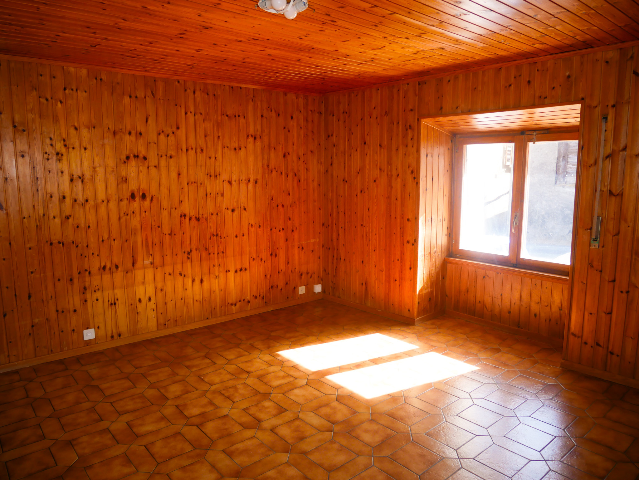 Holzgetäfelter leerer Raum mit Terrakottafliesen