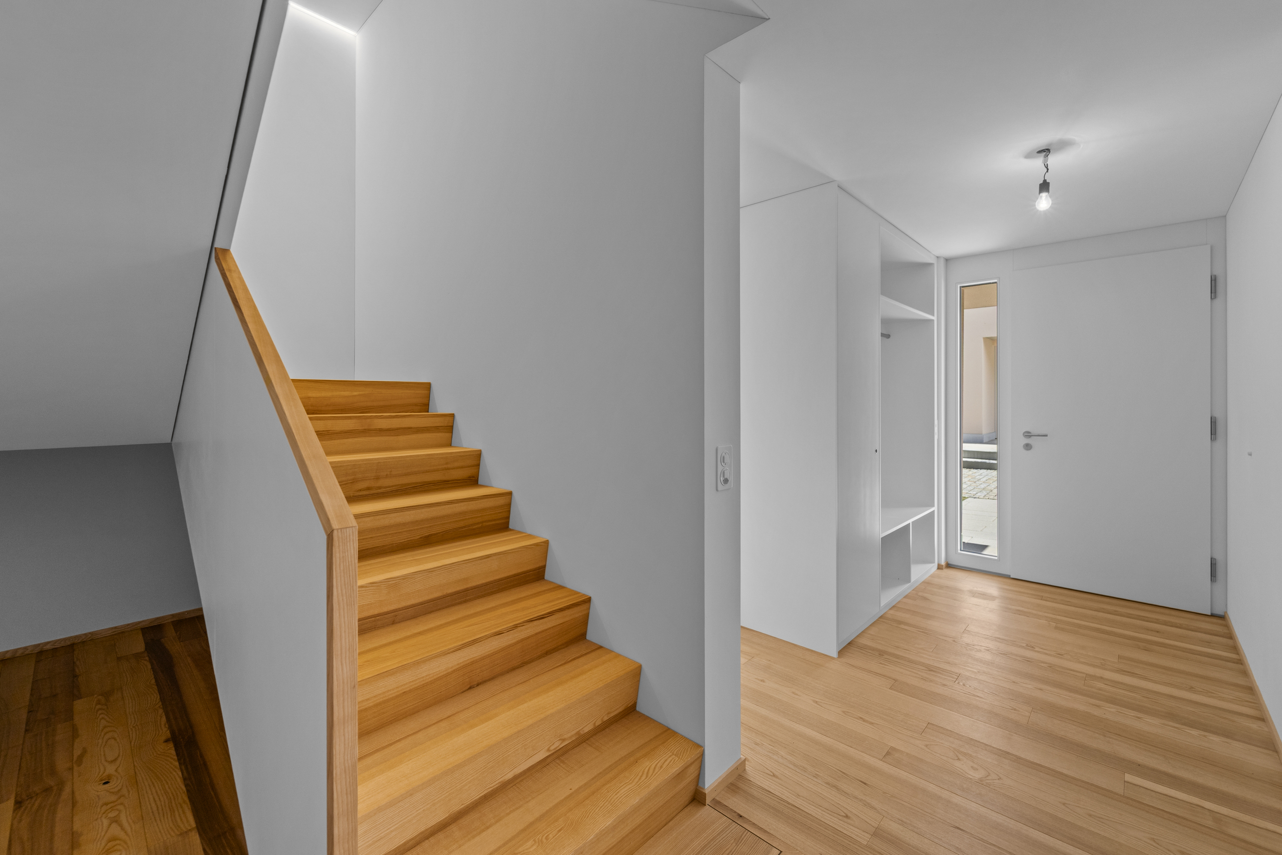 Heller Eingangsbereich mit Holztreppe