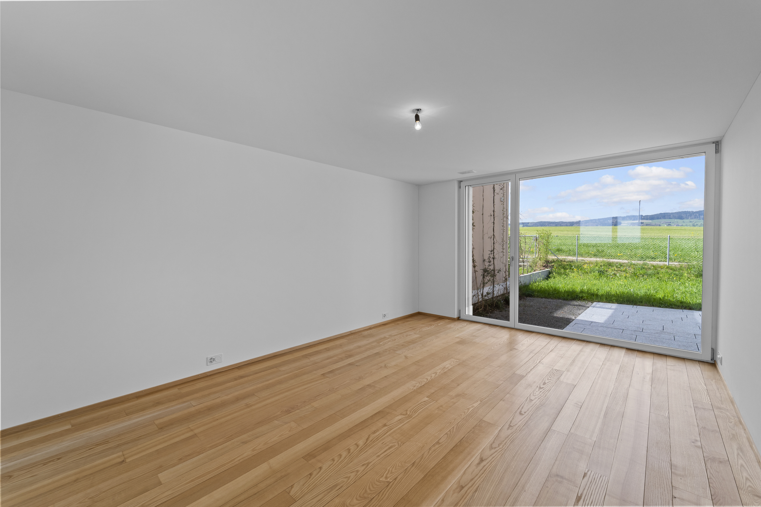 Leeres, helles Zimmer mit Blick ins Grüne
