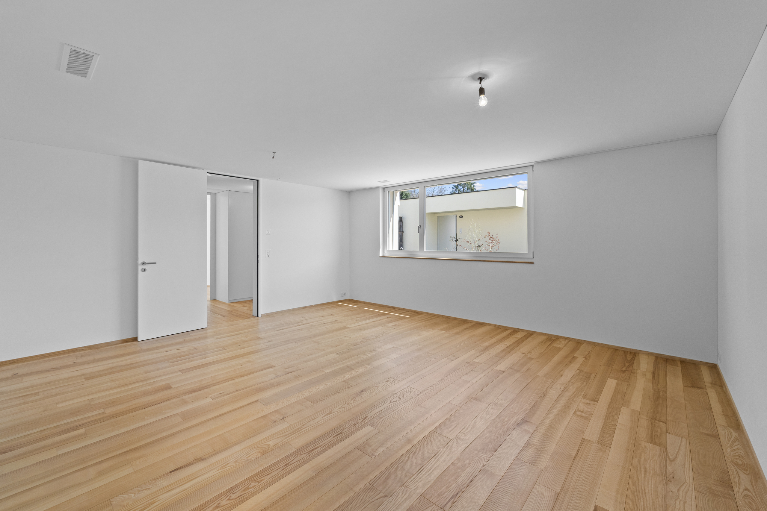 Leerer heller Raum mit Parkettboden und Fenster