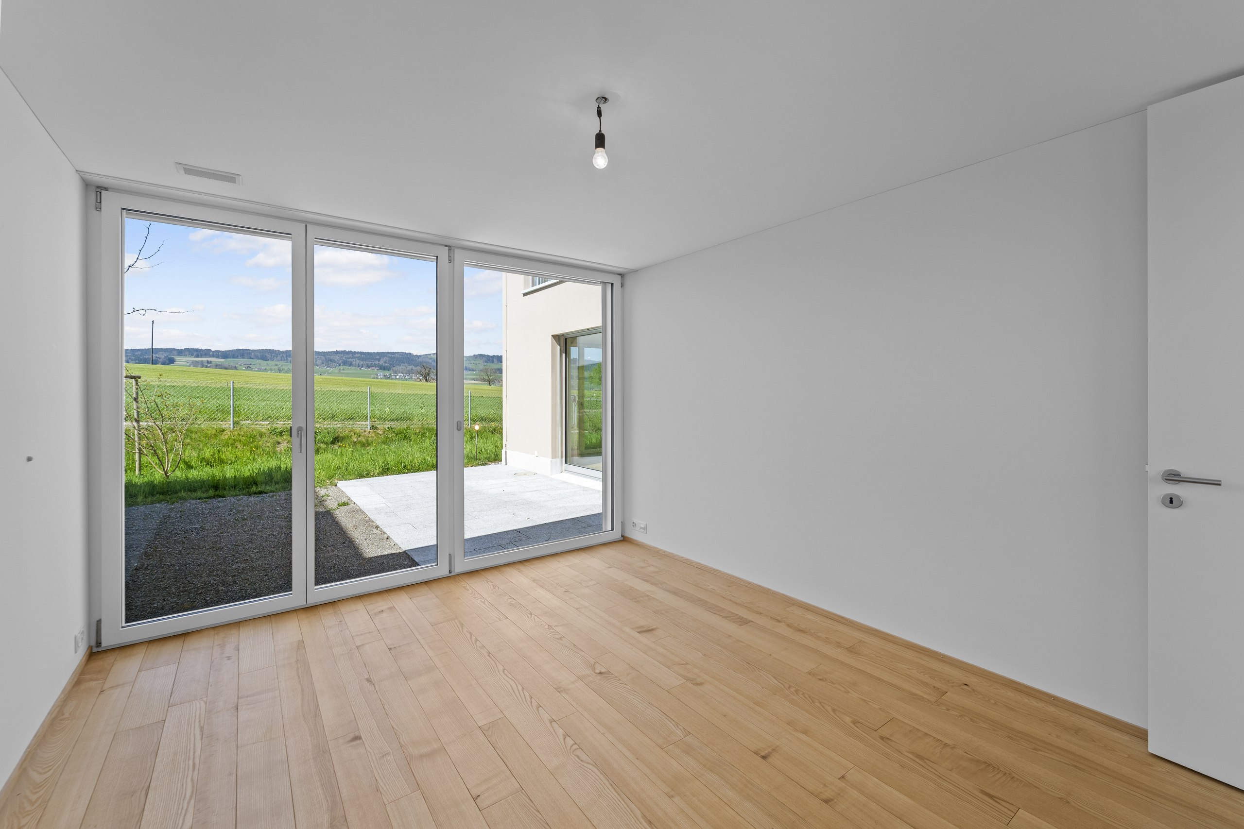 Leerer, heller Raum mit großem Fenster zur Landschaft
