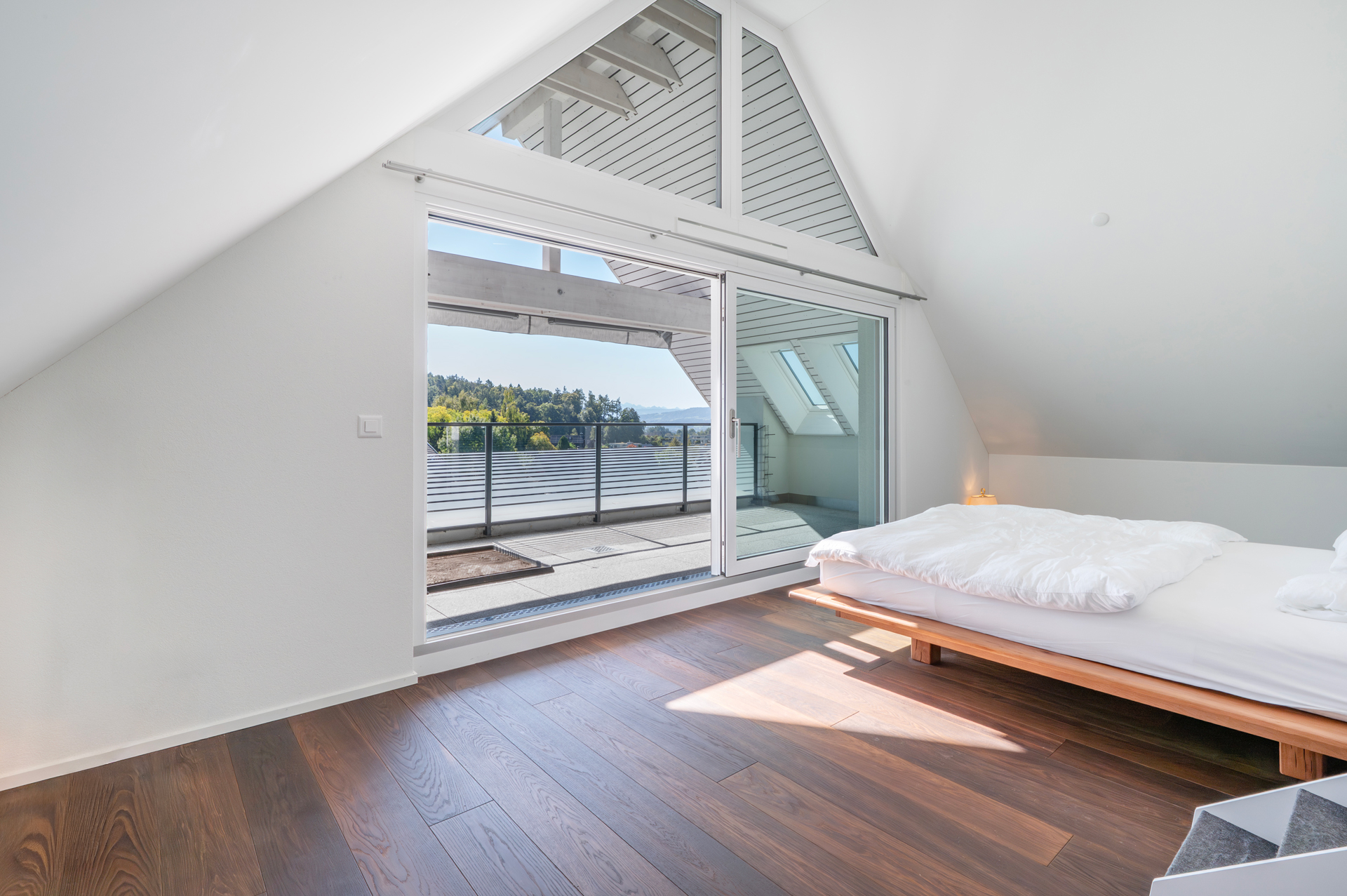 Helles Schlafzimmer mit Dachschräge und Balkonblick