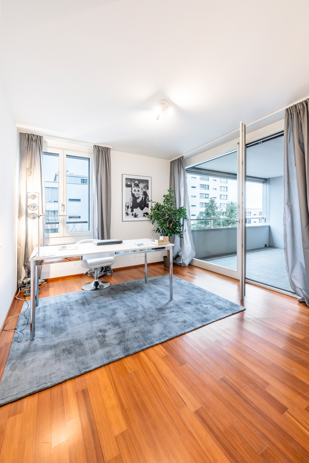Hell eingerichtetes Arbeitszimmer mit Balkonzugang