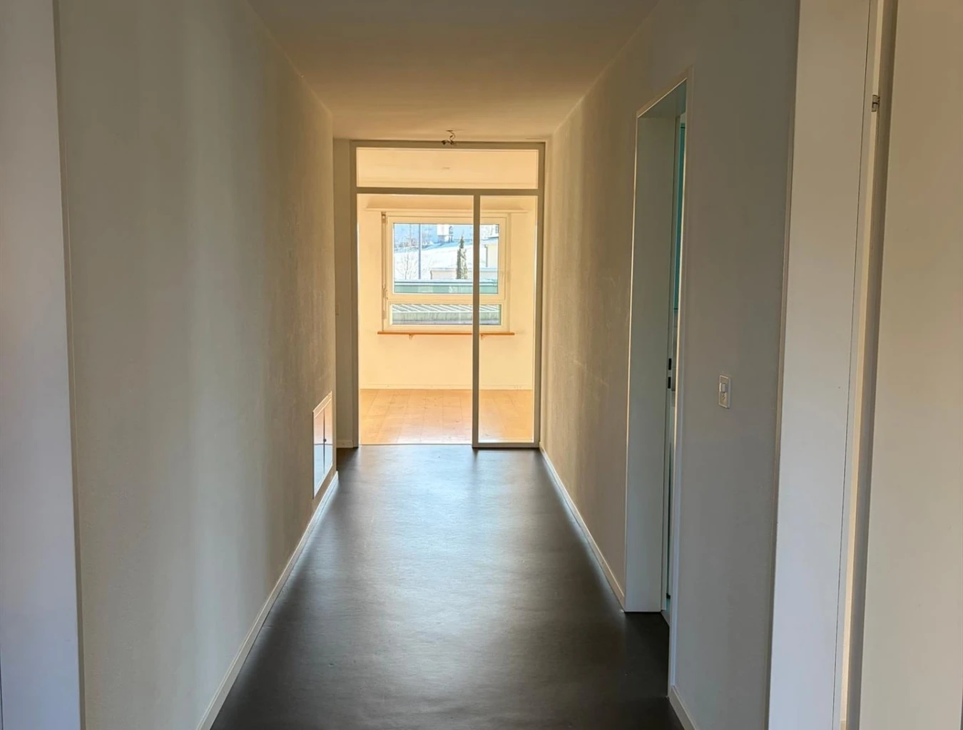 Langer Flur mit Blick in einen hellen Nebenraum