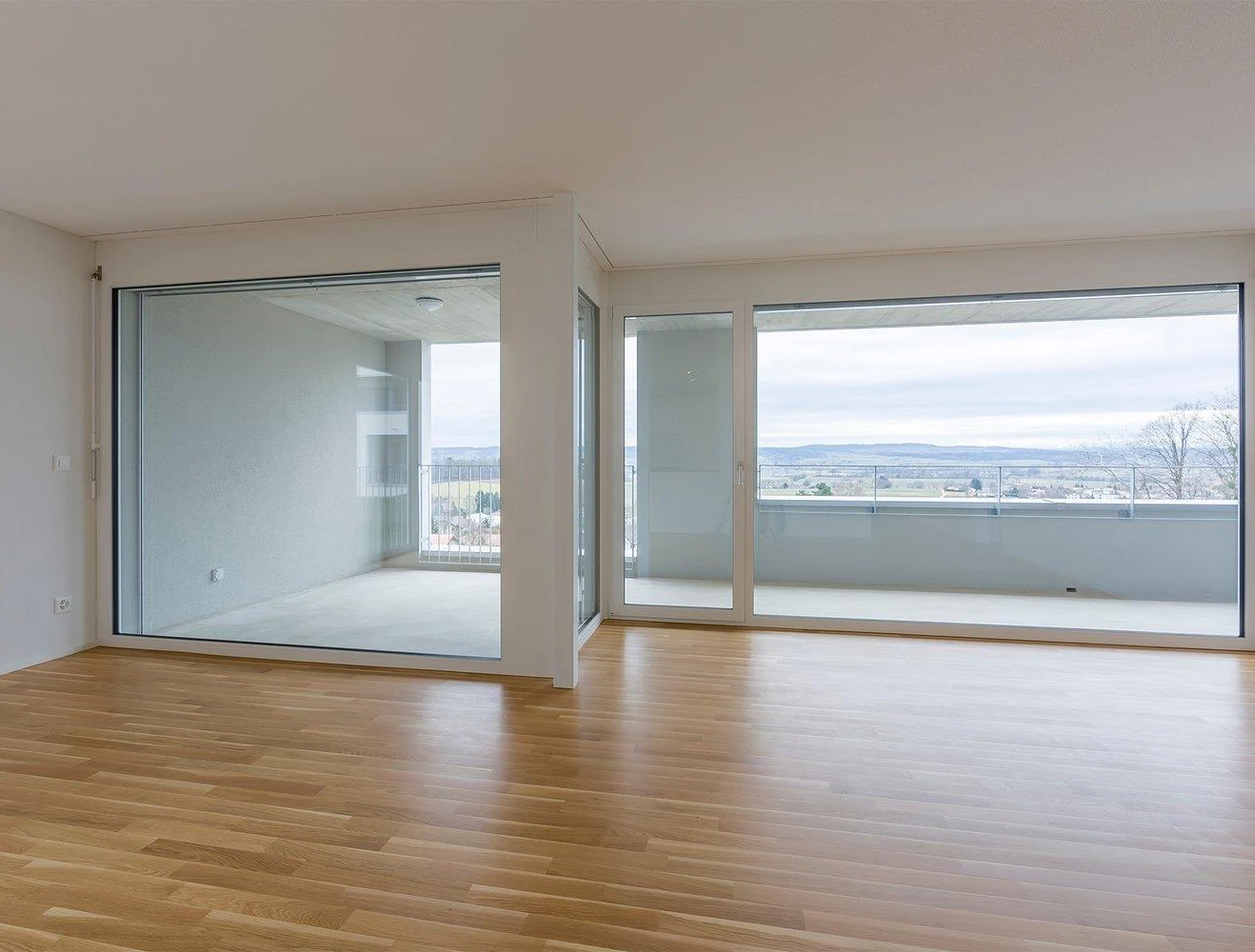 Heller leerer Wohnraum mit großer Verglasung und Weitblick