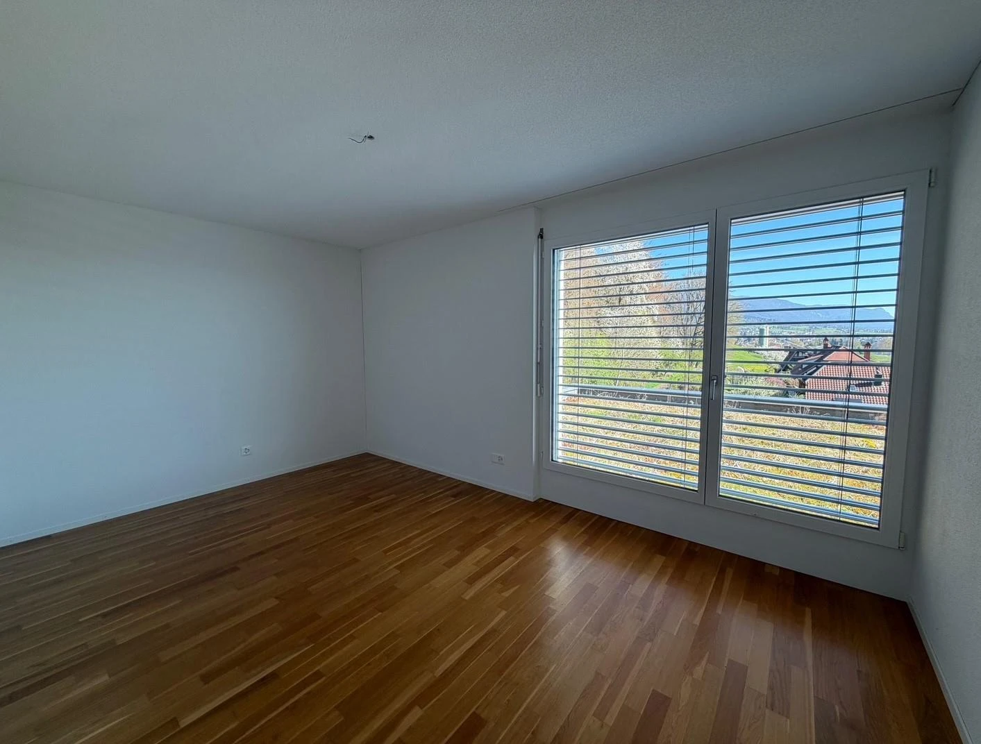 Heller leerer Raum mit großem Fenster und Holzboden