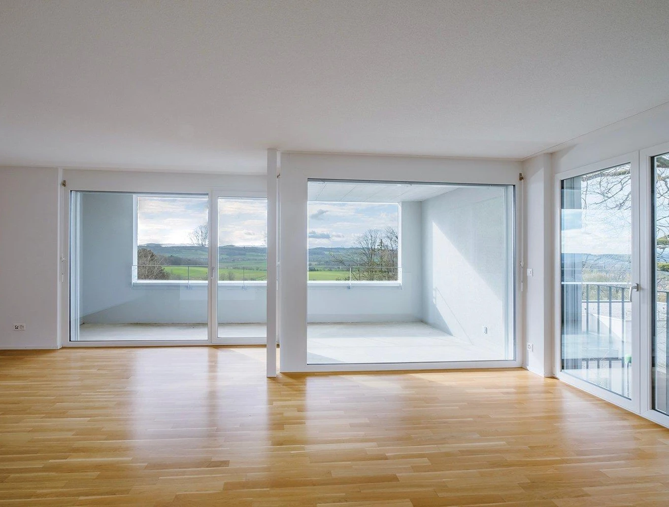 Heller Wohnraum mit großen Fensterfronten und Blick ins Grüne