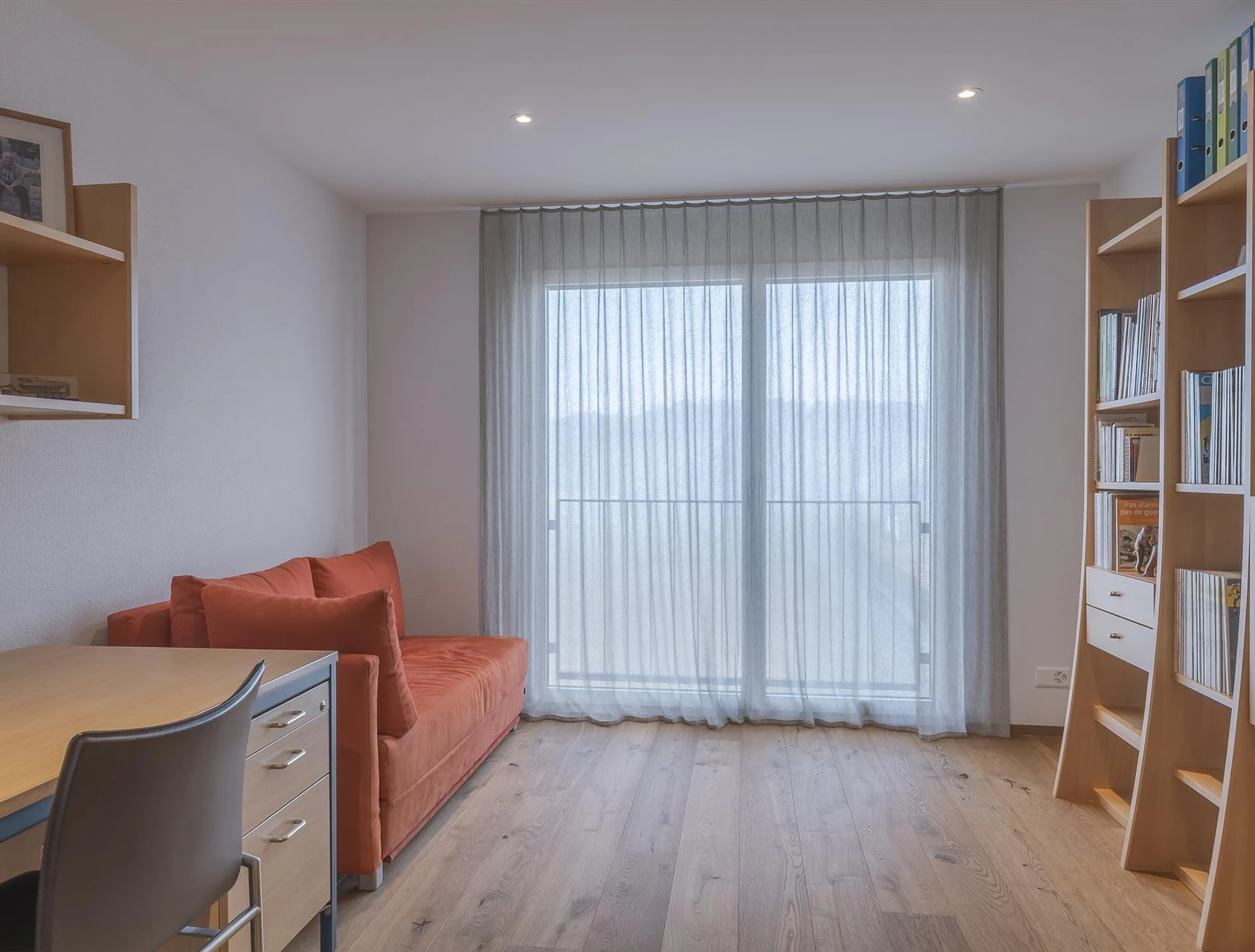 Arbeitszimmer mit Sofa und Regalwand