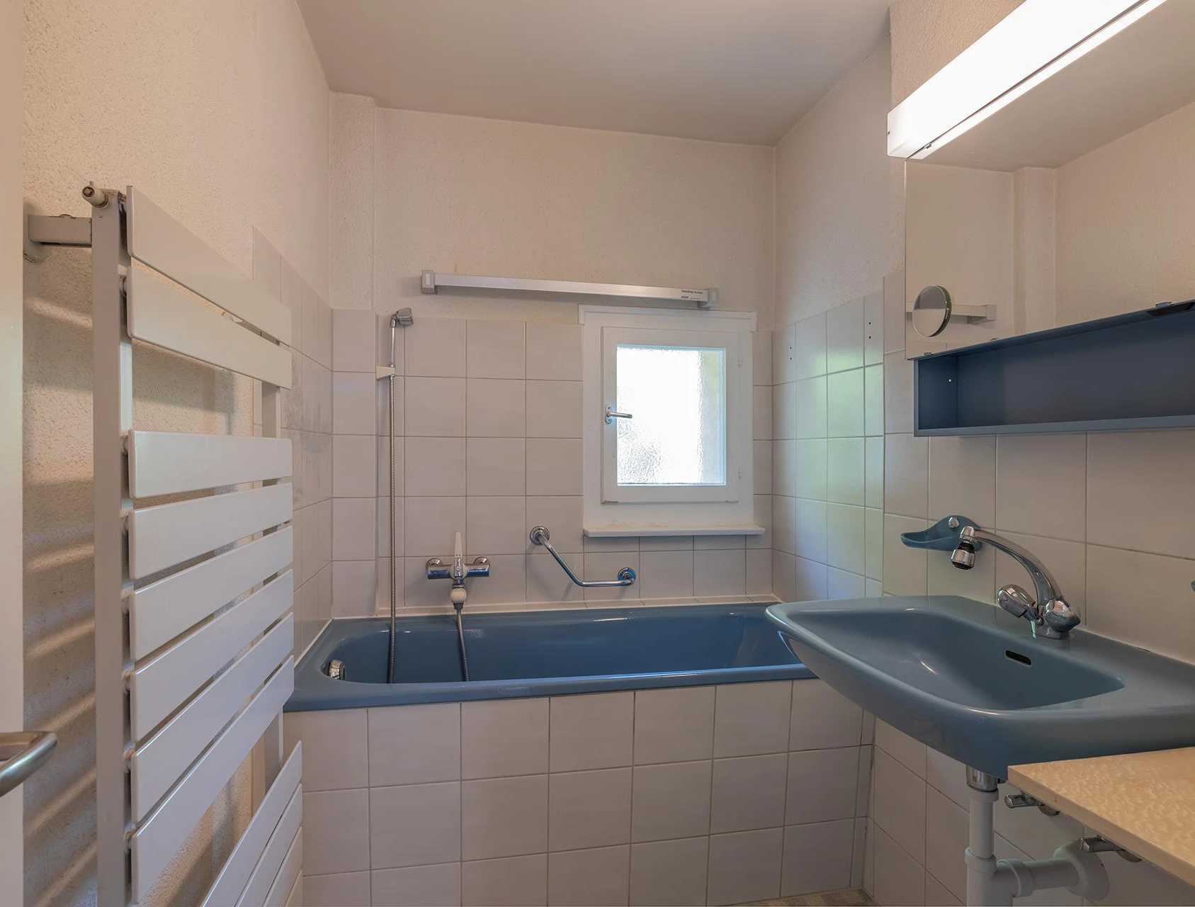 Kleines Badezimmer mit Badewanne und blauem Waschbecken
