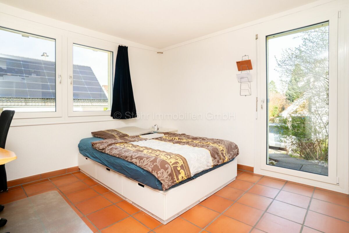 Schlafzimmer mit Fliesenboden und großen Fenstern