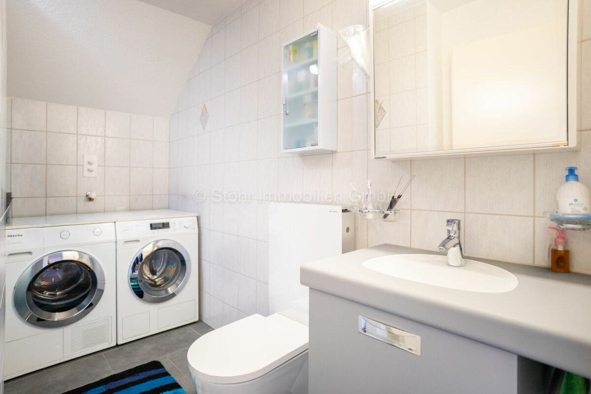 Modernes Badezimmer mit Waschtisch und Waschmaschinenbereich